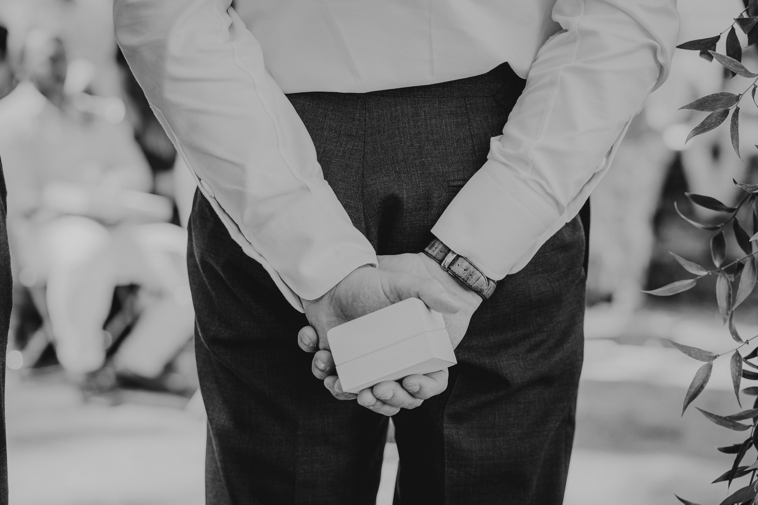 A groom's hands holding a wedding ring.