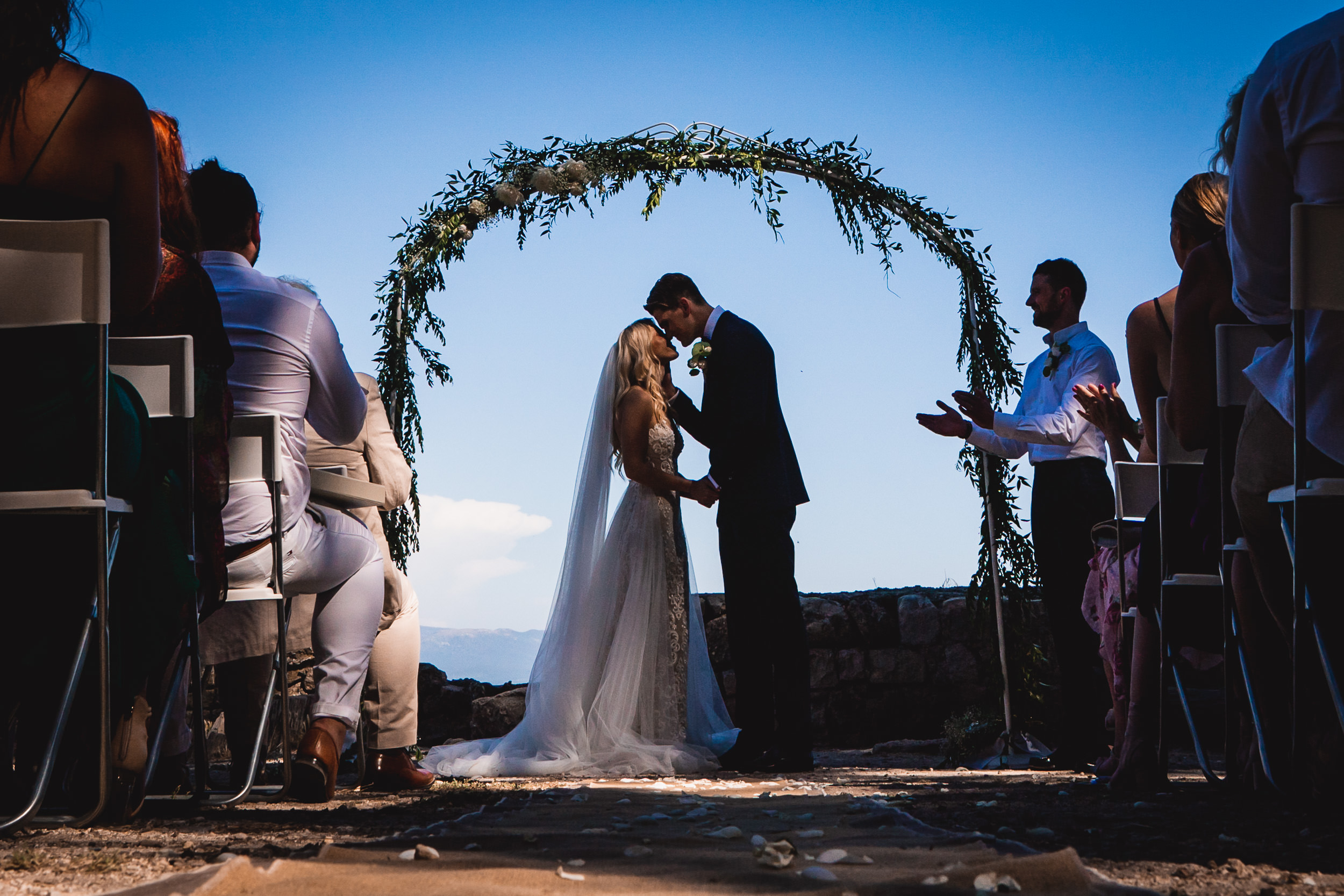 A bride and groom capture a kiss during their wedding ceremony in a beautiful wedding photo.