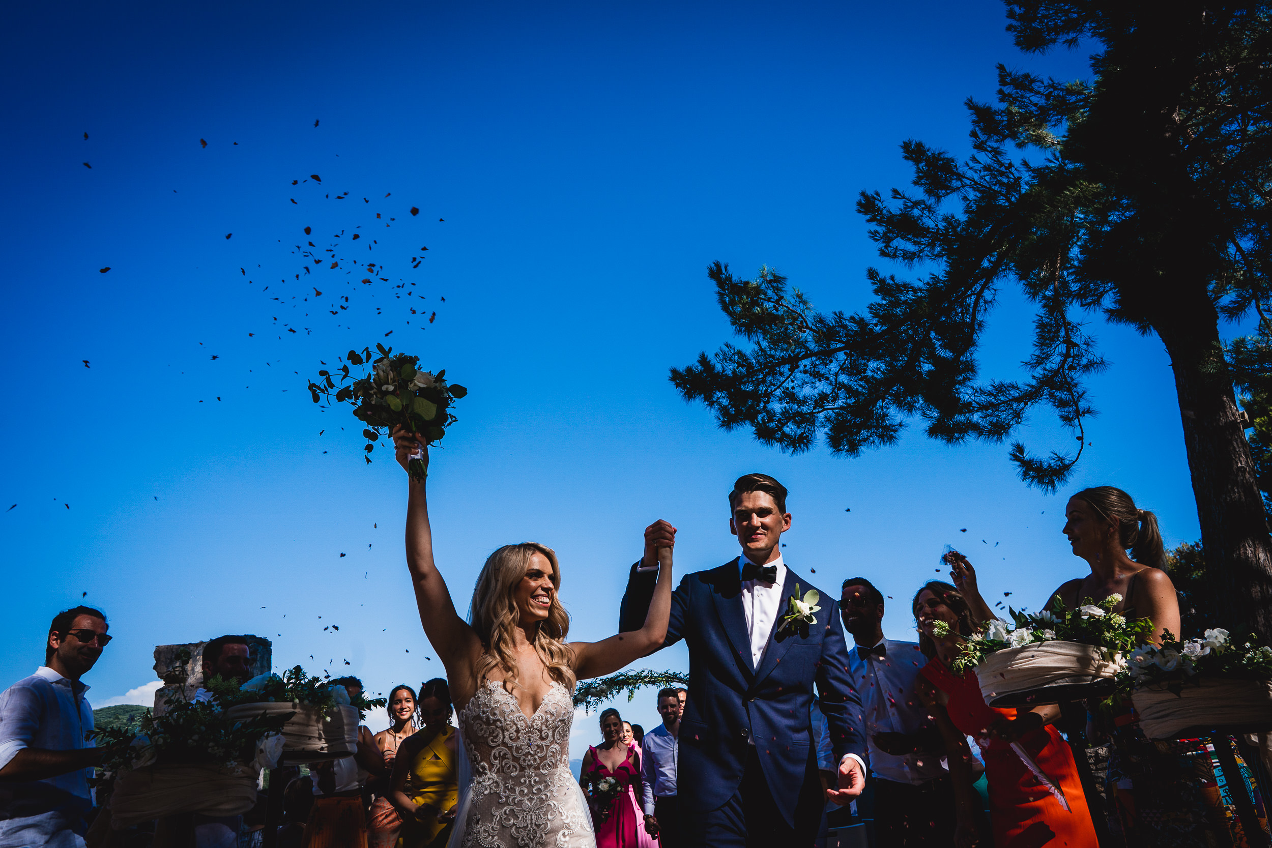 A wedding photographer captures a bride and groom playfully throwing confetti during their ceremony.