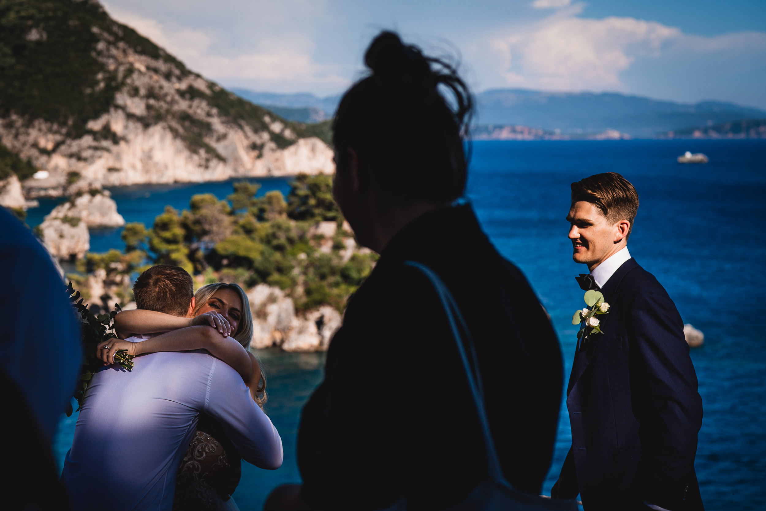 A wedding couple standing on a cliff overlooking the sea.