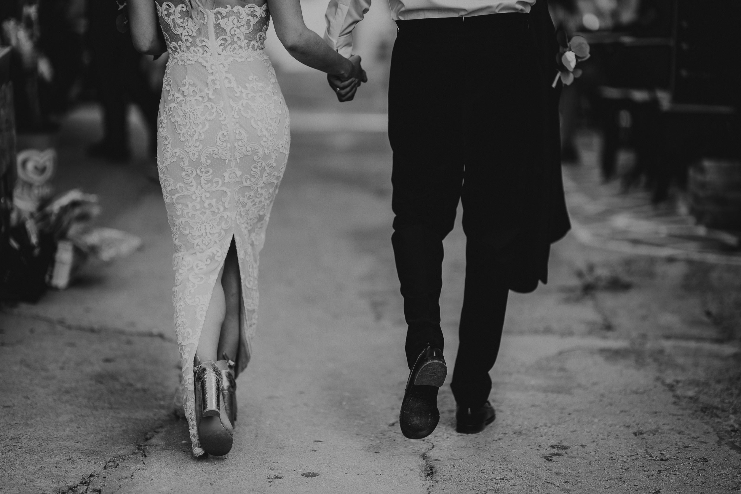Wedding photographer captures stunning black and white portrait of a bride and groom strolling down the street.