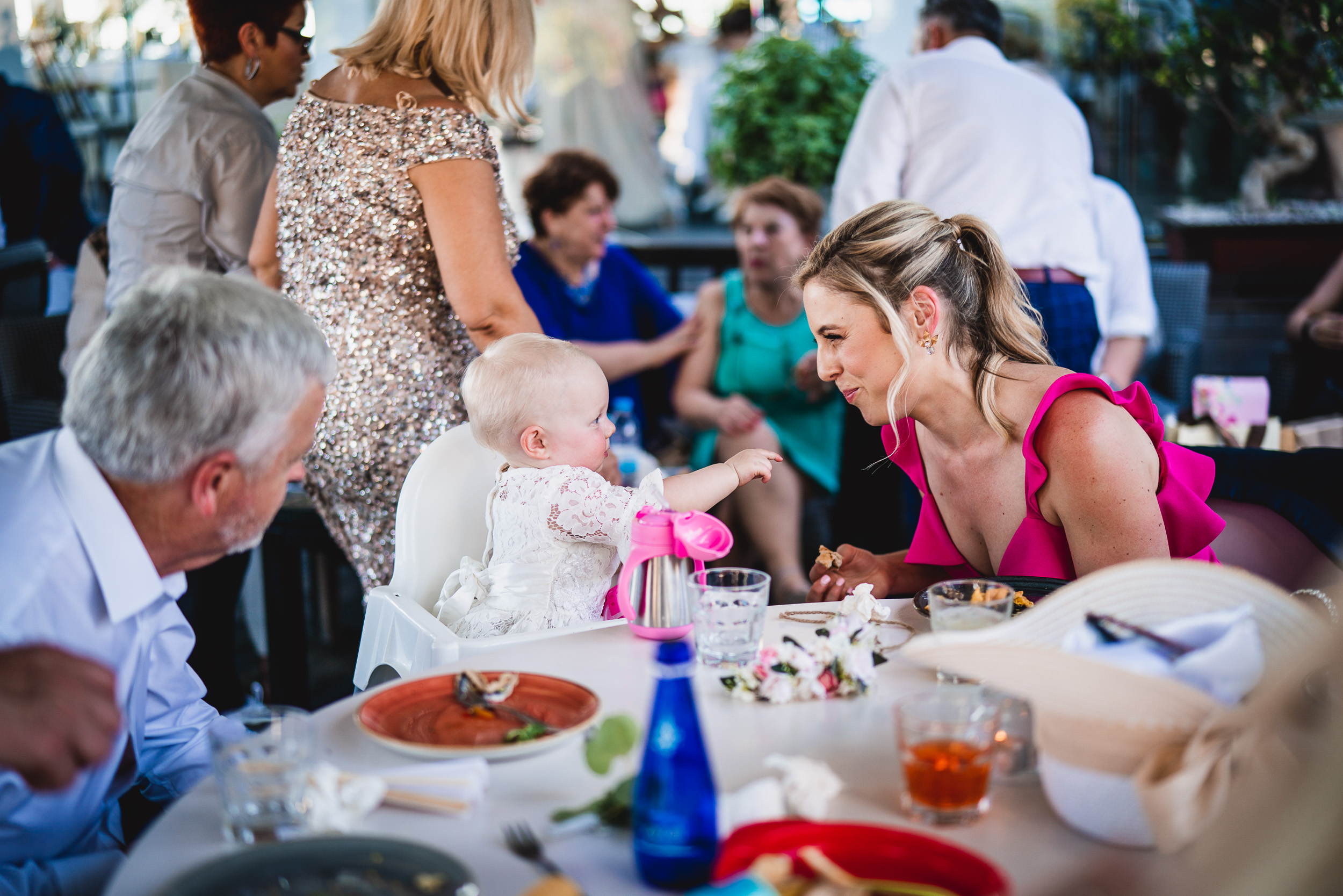A woman with a baby sits at a table with other guests at a wedding reception.