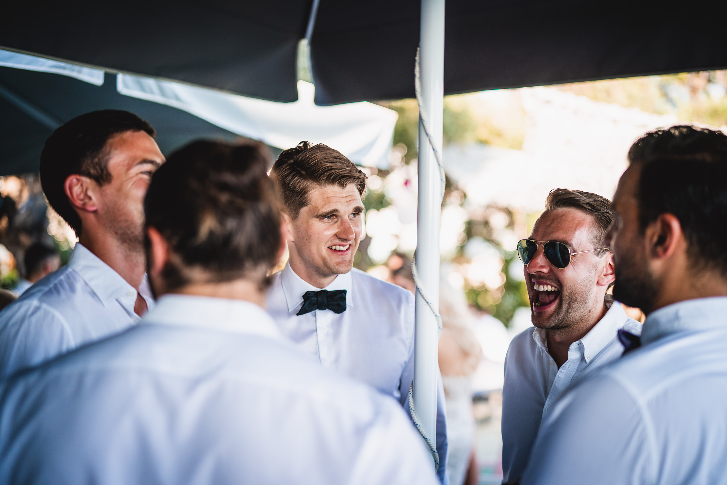 A group of groomsmen laughing at each other during a wedding photo shoot.