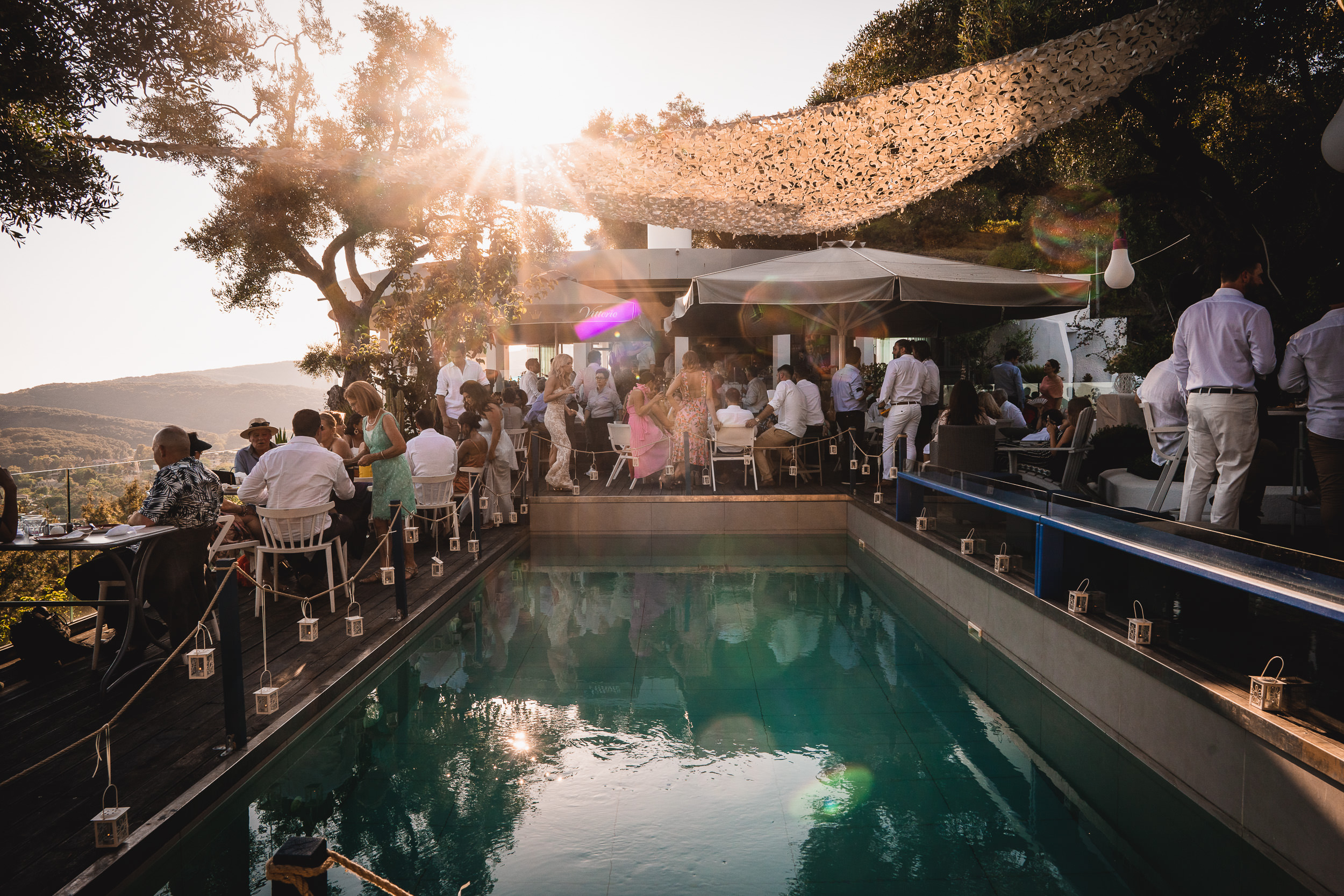 A wedding photographer capturing a bride's image by the poolside.