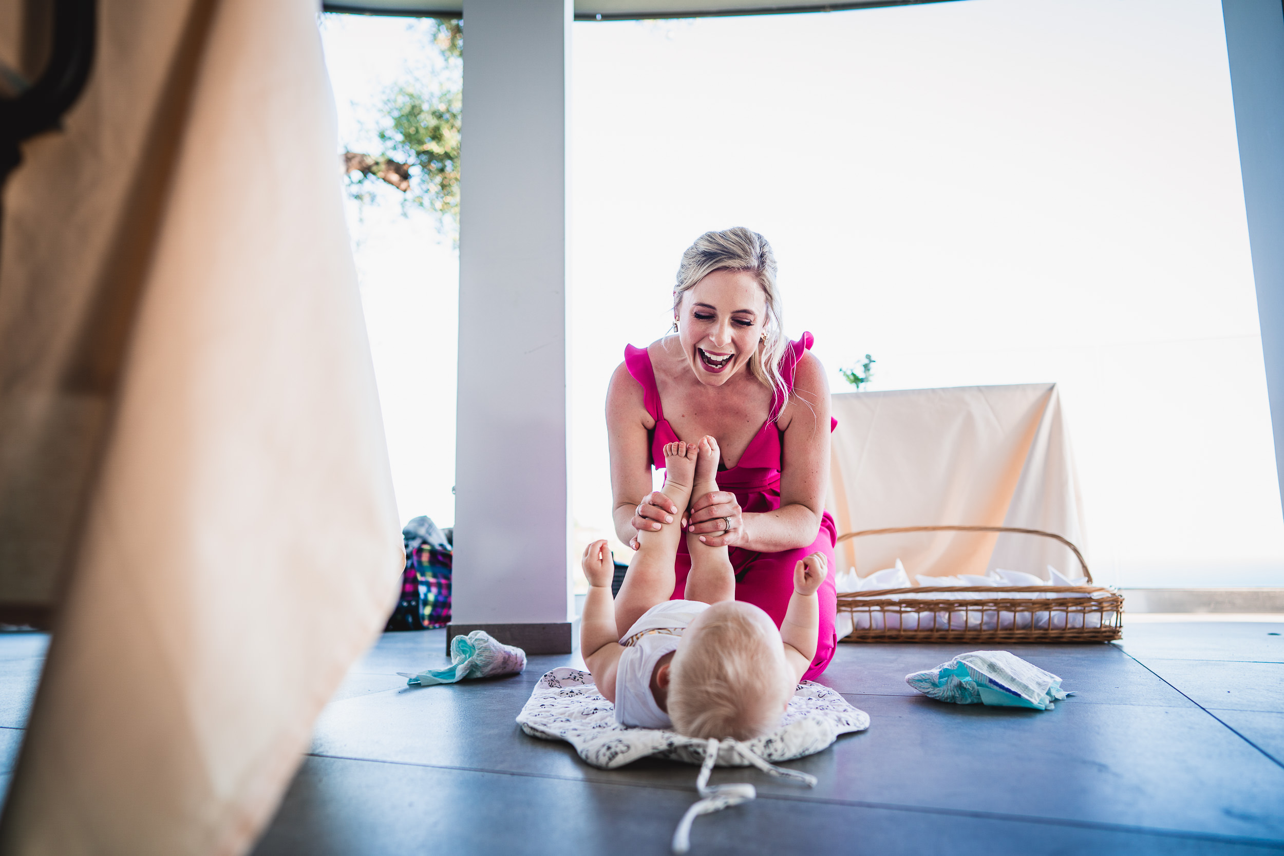 A wedding photographer captures a heartwarming moment as a woman plays with a baby on the floor.