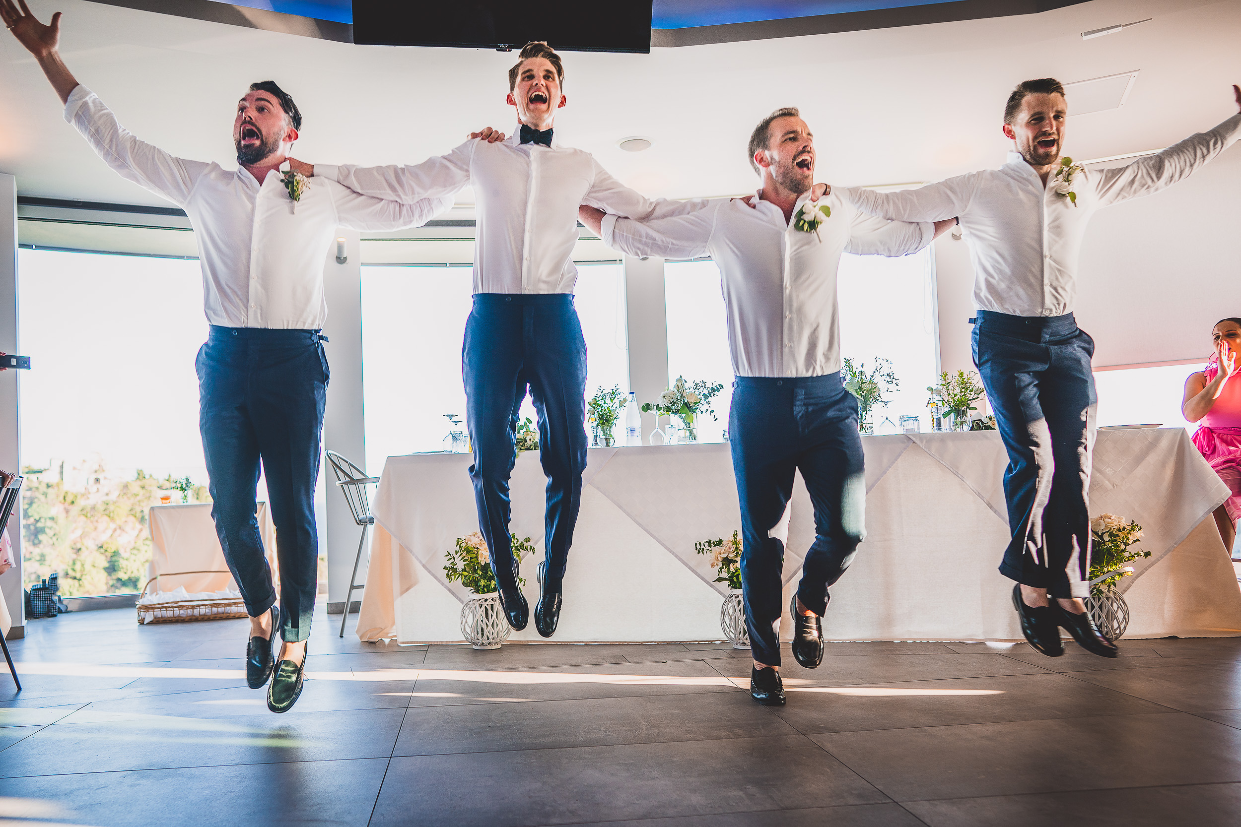 Groomsmen's joyful leap during wedding celebration.