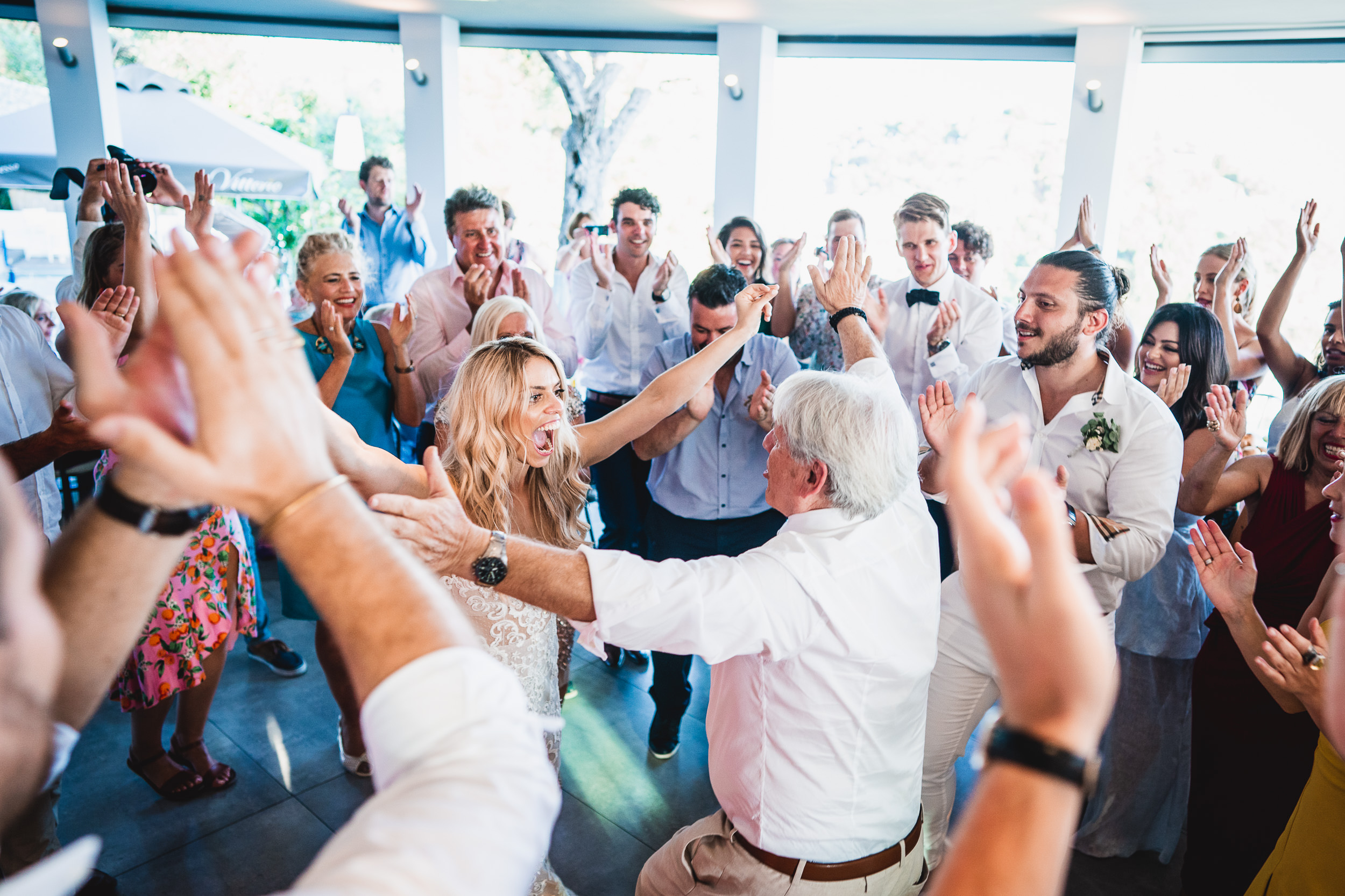 A group of people dancing at a wedding reception with the bride and groom.