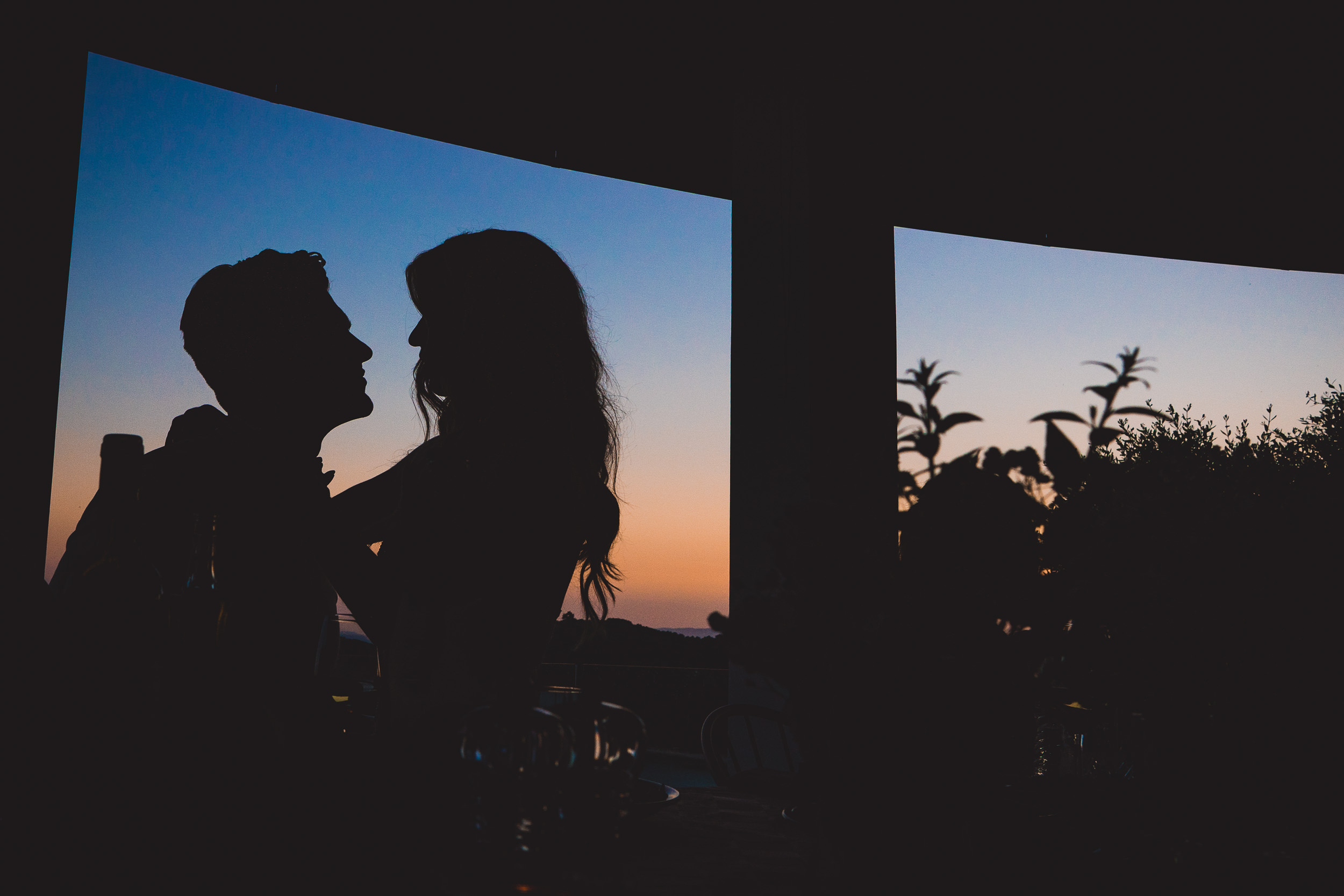 A groom and his bride captured in a romantic sunset kiss by their wedding photographer.