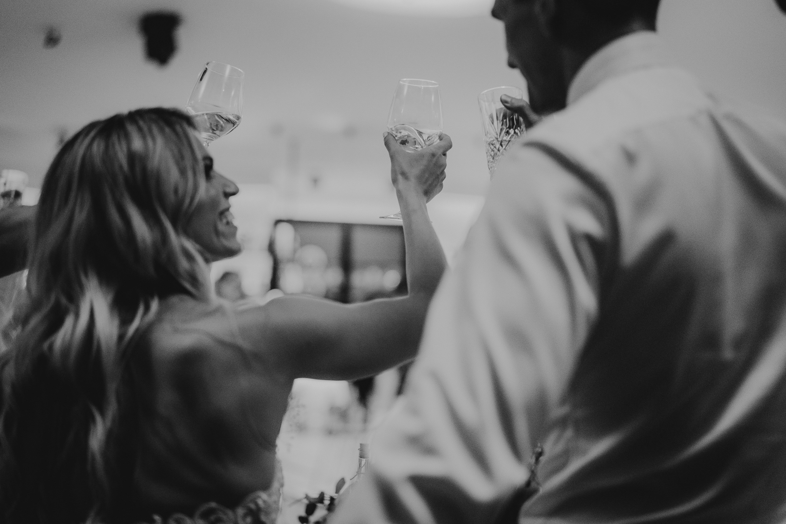A bride and groom, captured beautifully by their wedding photographer while toasting at their reception.