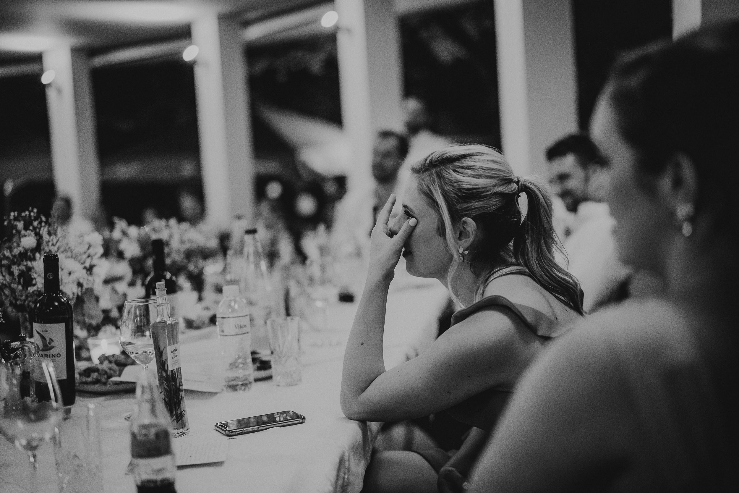 A bride is crying while sitting at a table at her wedding.
