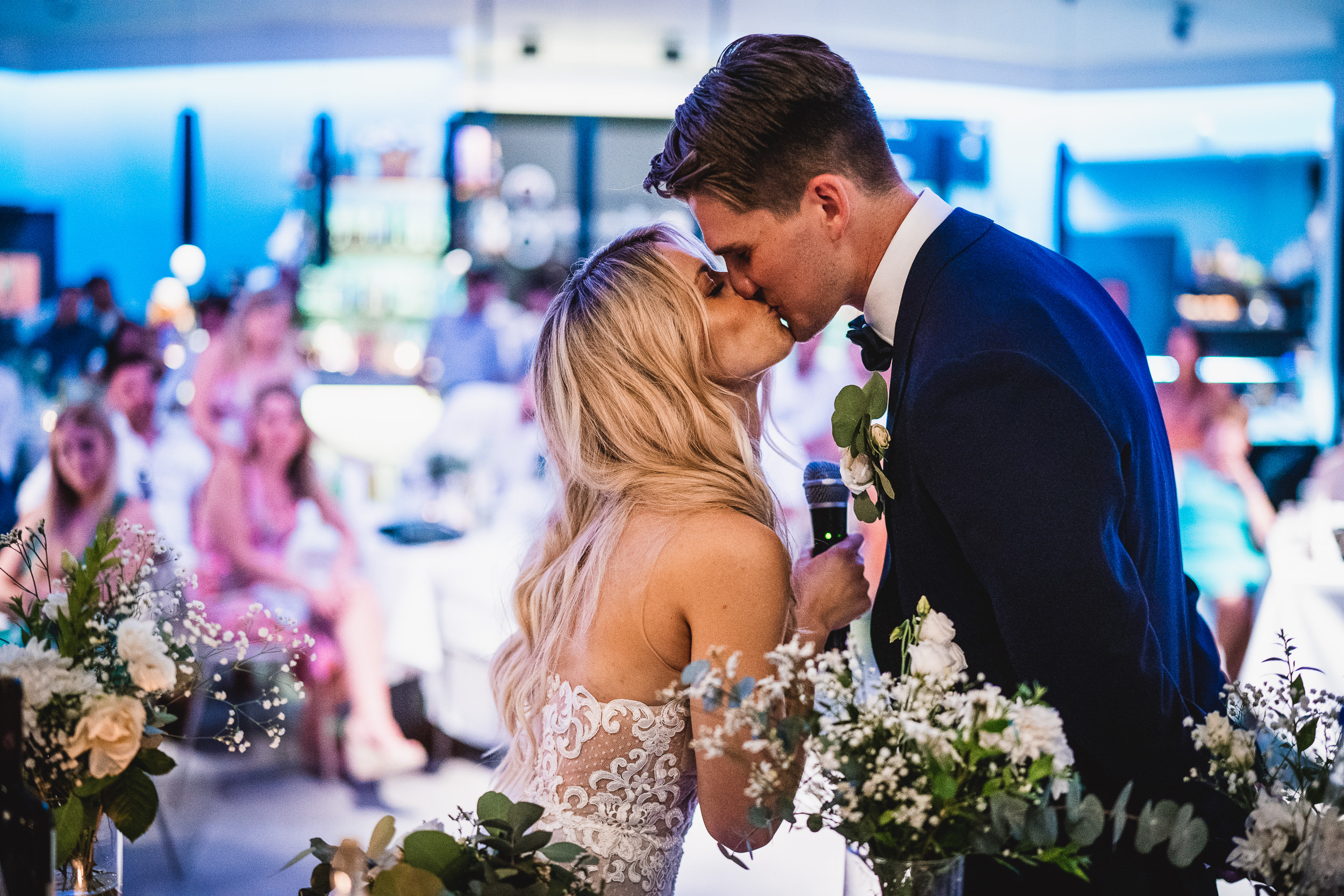 A wedding photographer captures a photo of a bride and groom kissing during their reception.