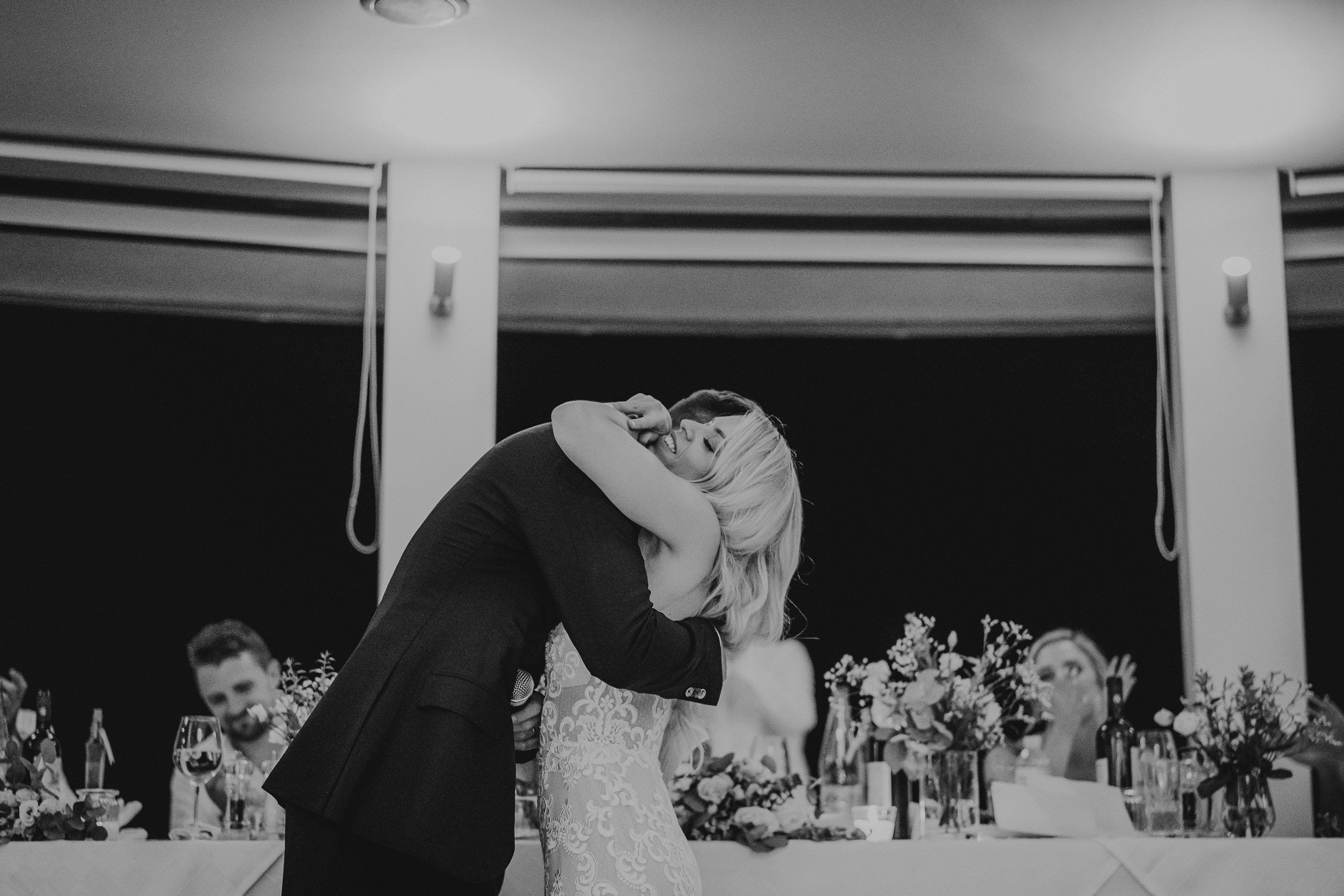A wedding photographer capturing a bride and groom kissing during their wedding reception.