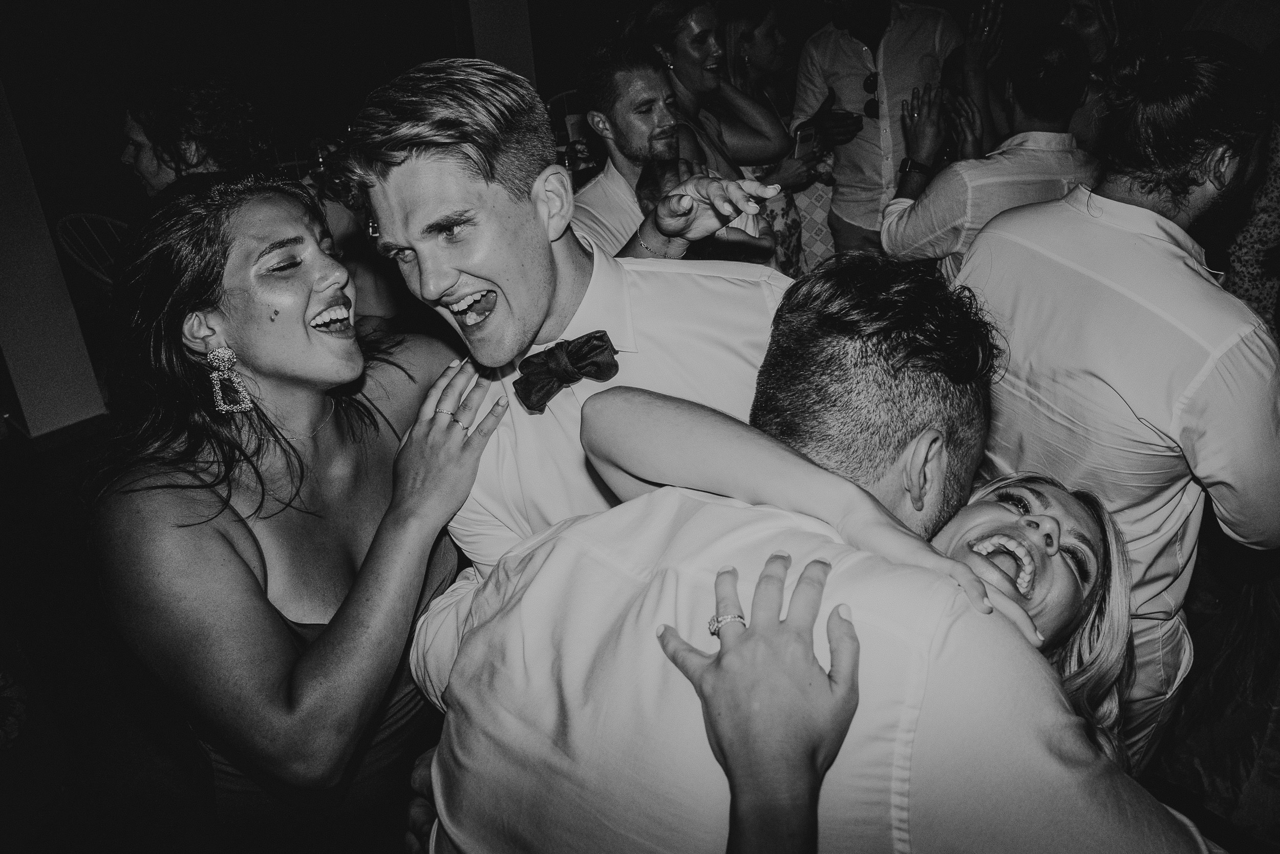 A black and white photo of a bride and groom dancing at their wedding party.