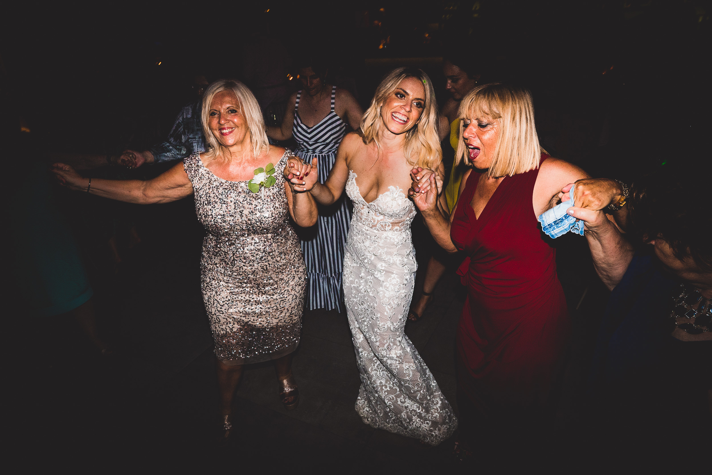 A group of women dancing at a wedding reception captured by a wedding photographer.
