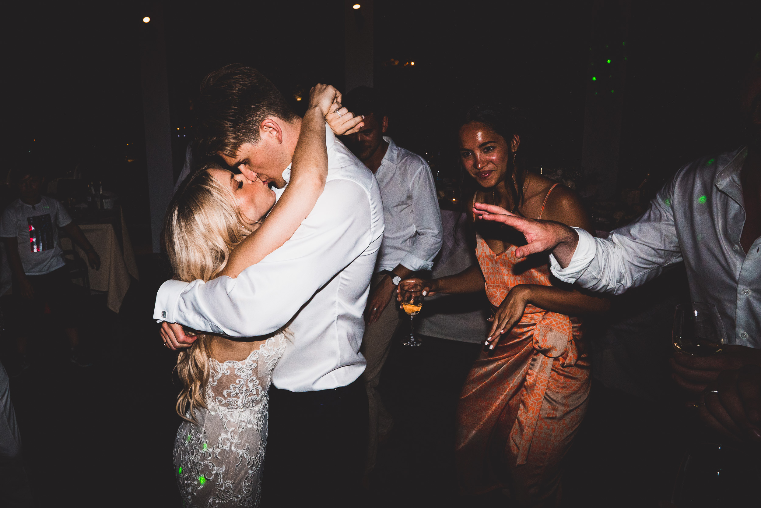 A wedding photographer captures a bride and groom sharing a kiss on the dance floor.