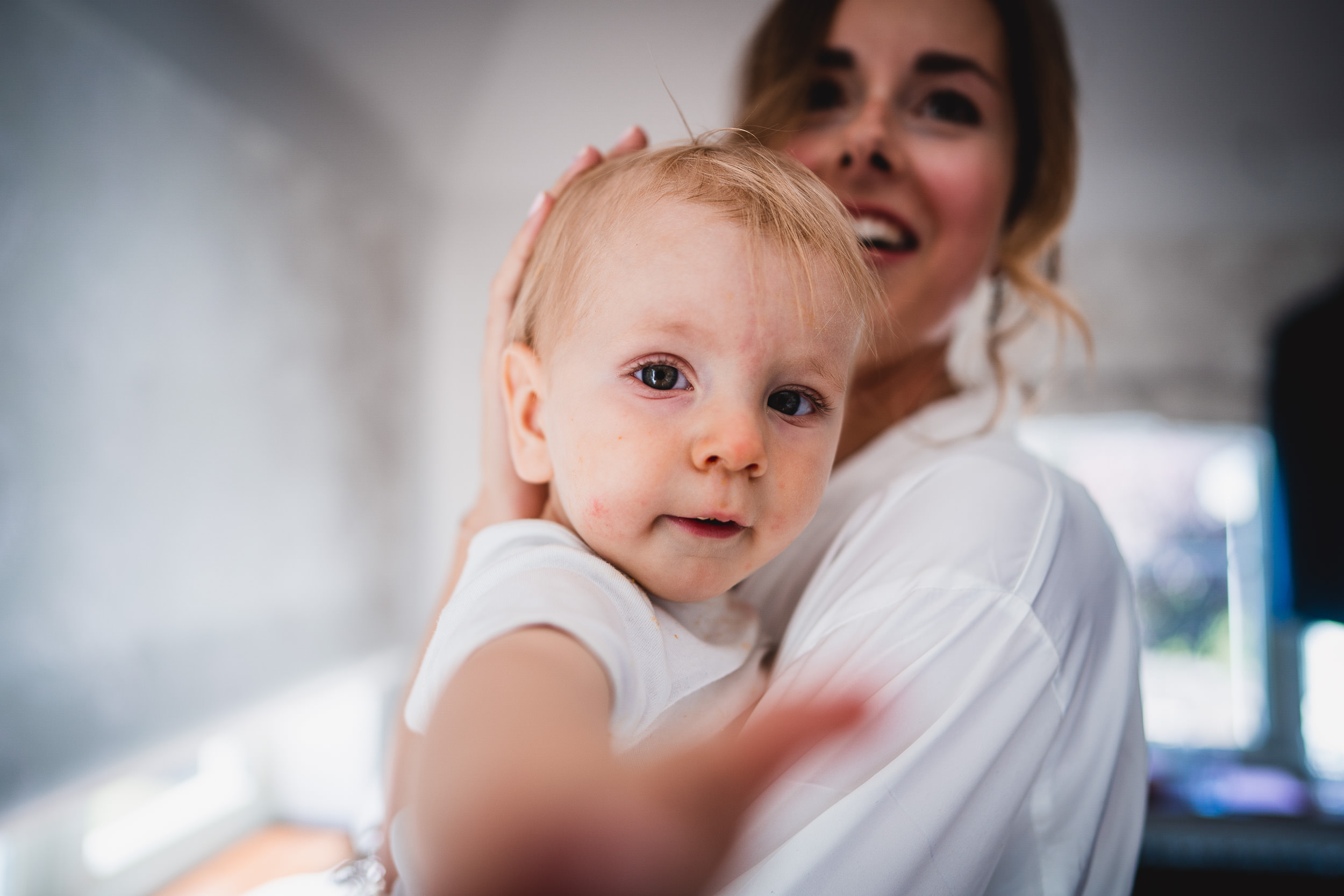 A bride holding a baby in her arms during her wedding photo session.