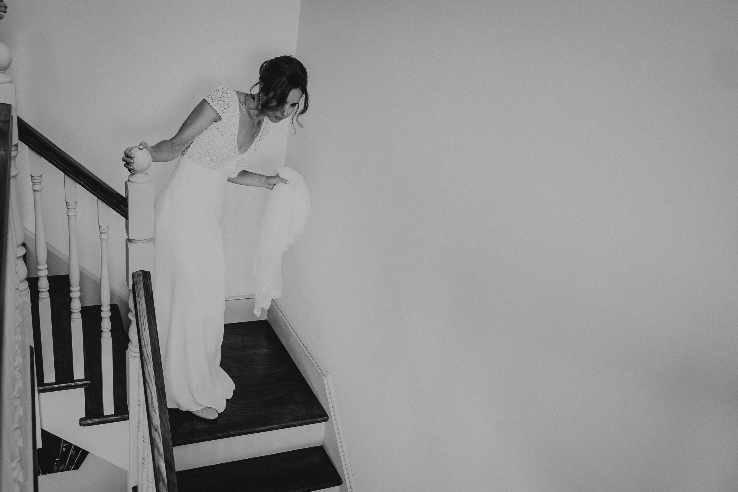 A wedding photo capturing a bride gracefully descending the stairs in her elegant white dress.