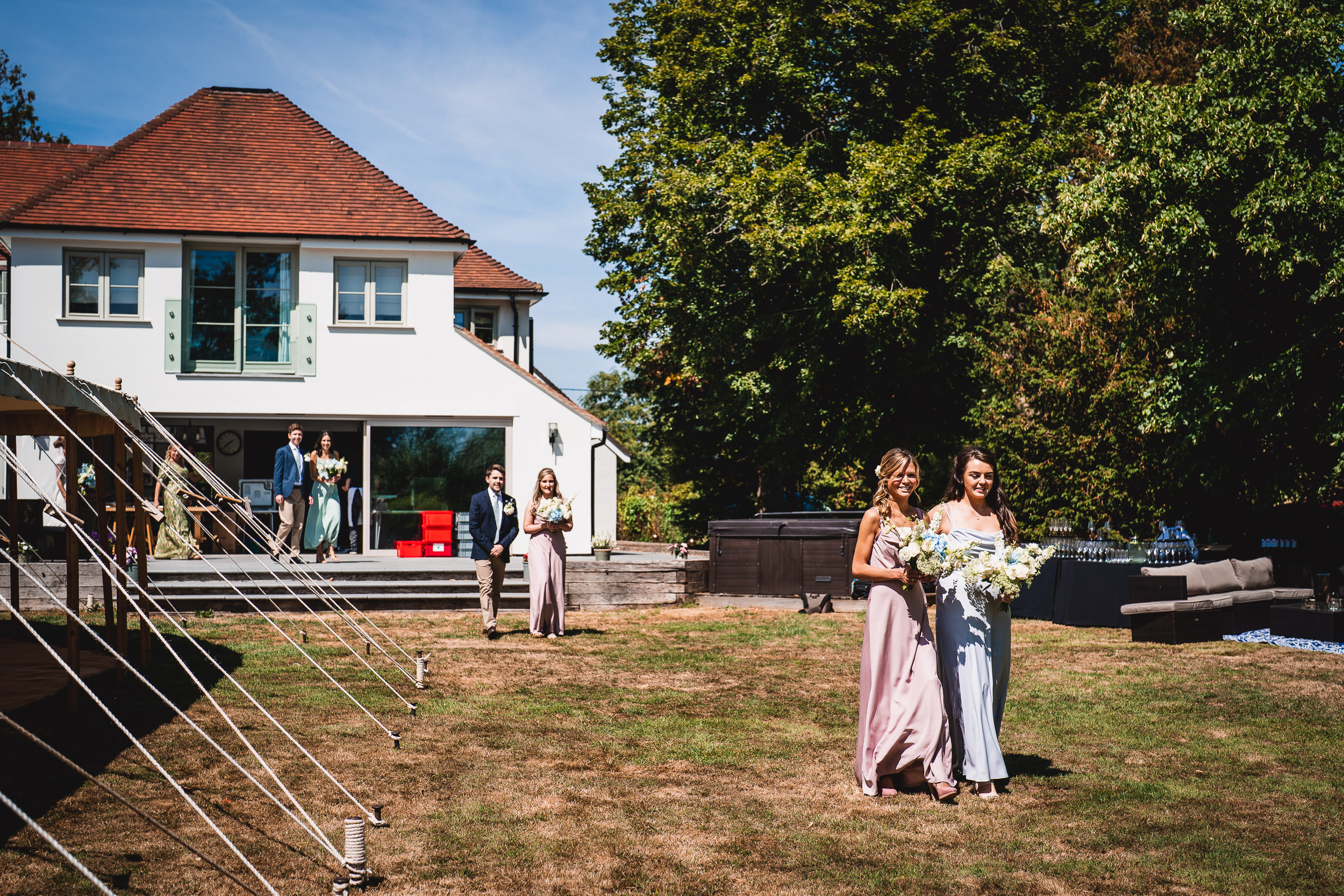 A group of bridesmaids walking in front of a house captured by a wedding photographer.