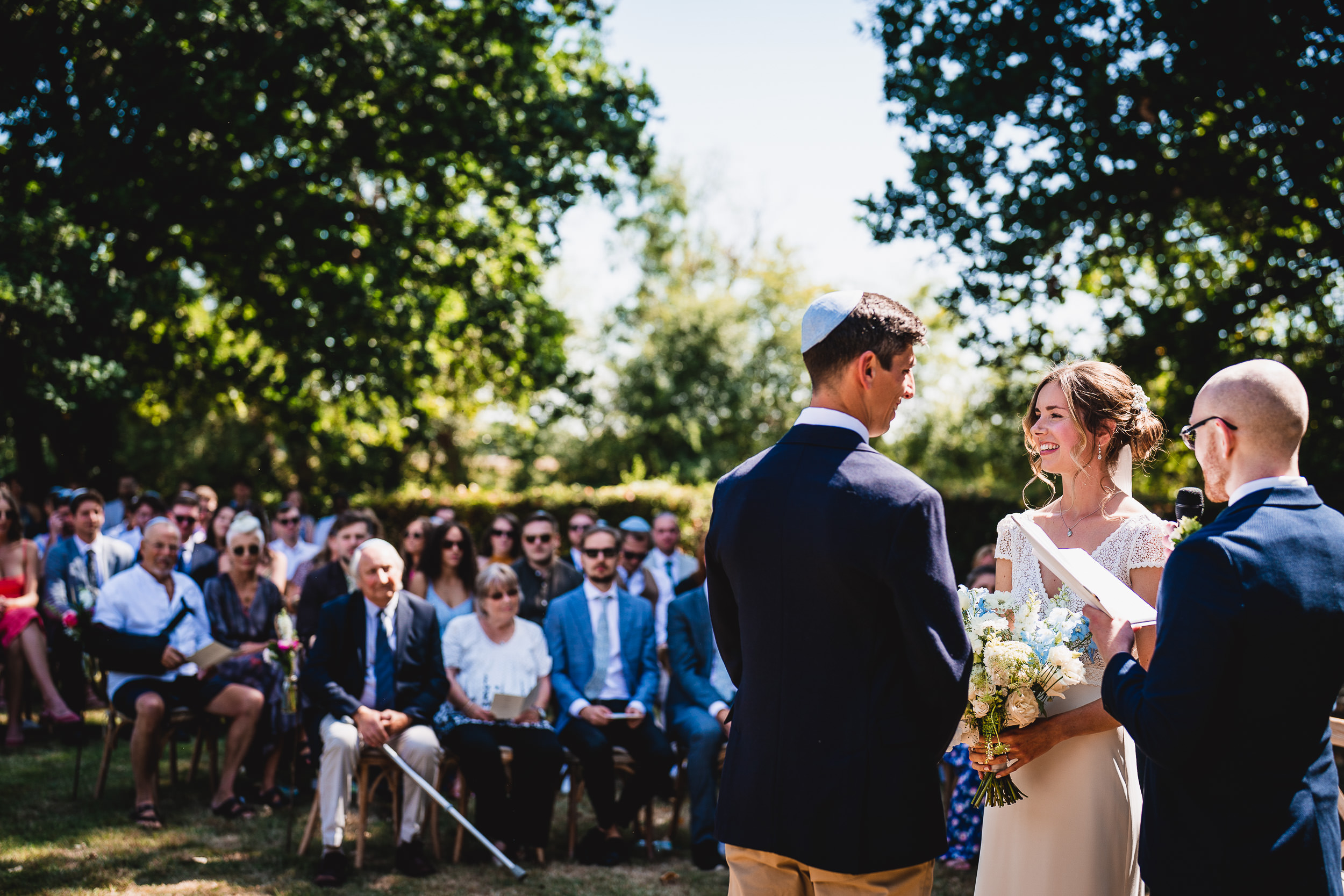 A bride and groom capture their vows with the help of a wedding photographer during their outdoor wedding ceremony.