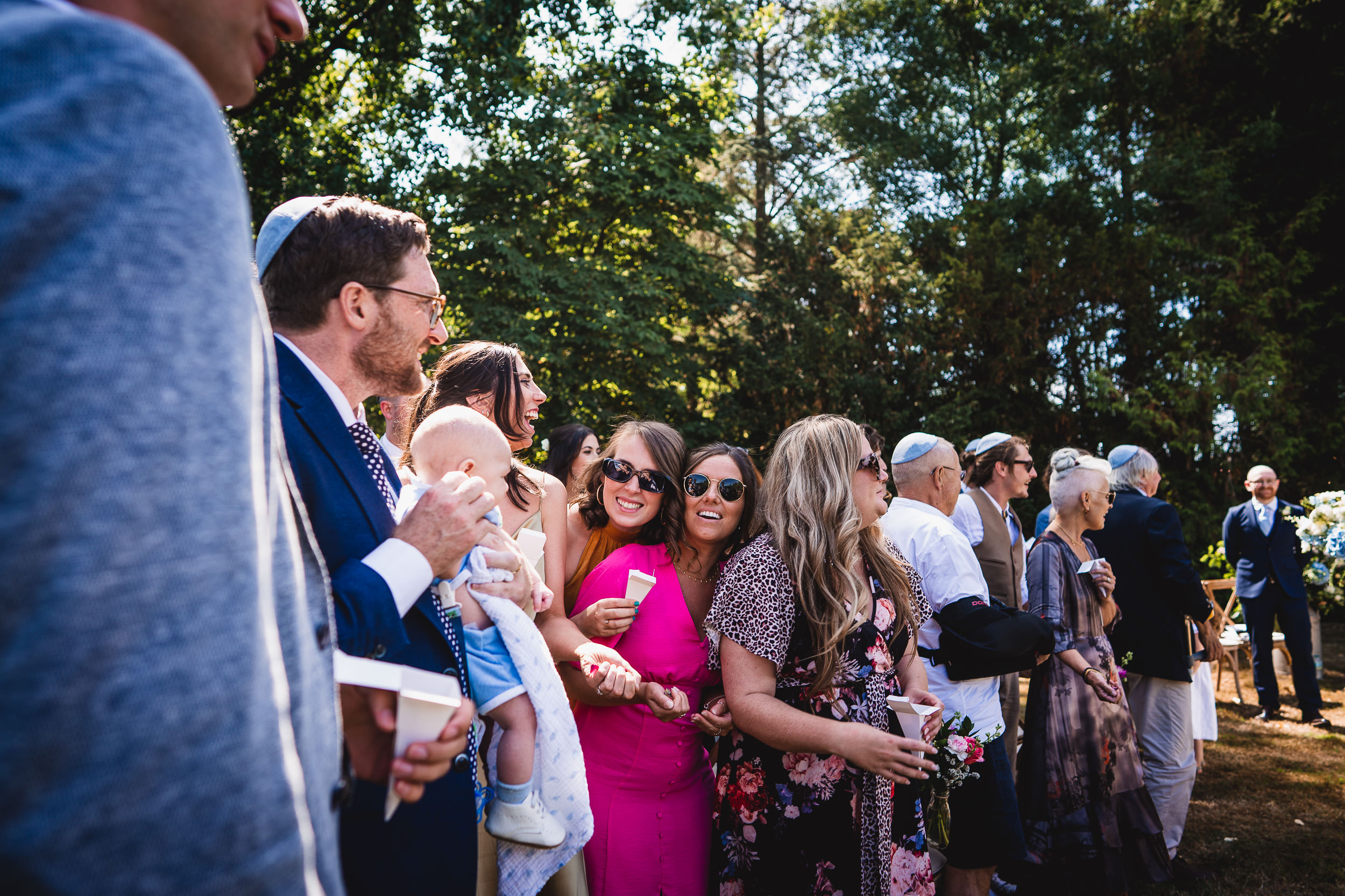 A line of people posing for a wedding photo with the bride.