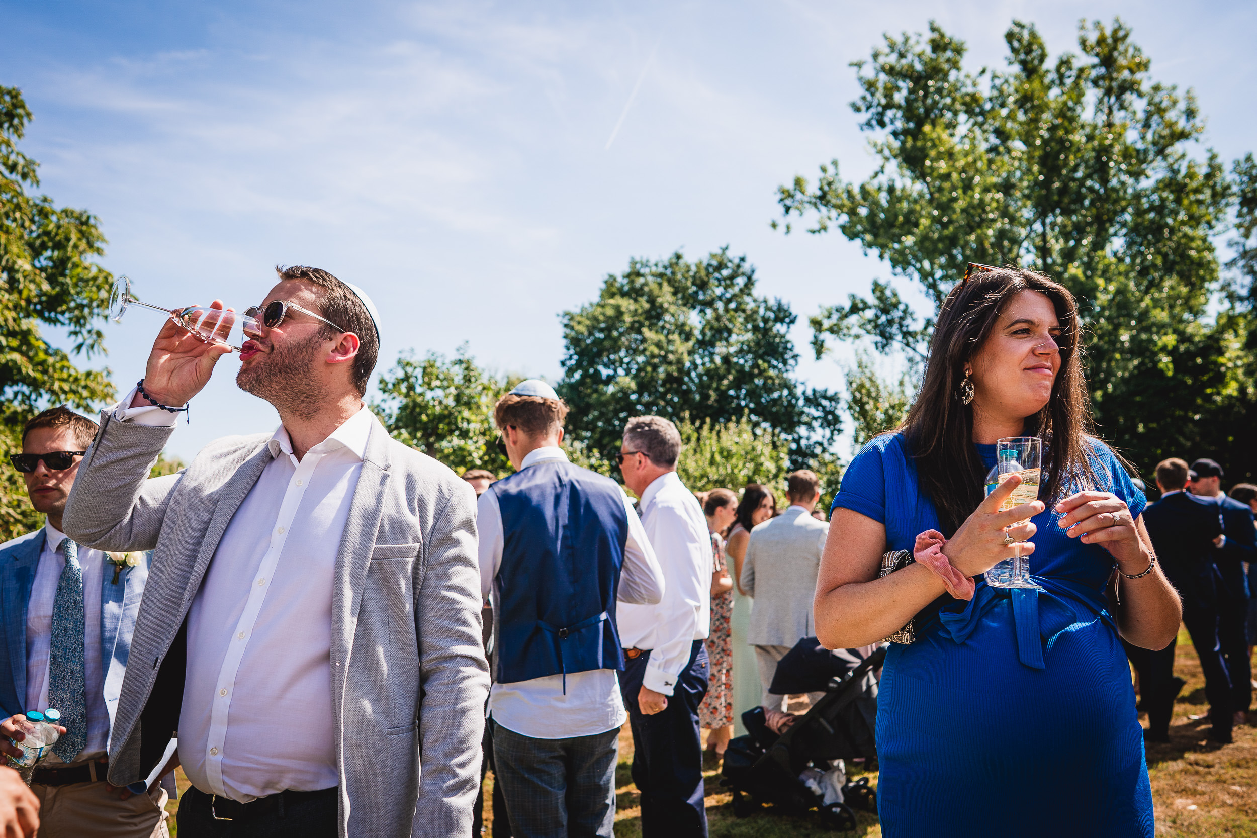 A group of people celebrating at a wedding, toasting with wine while the groom smiles.