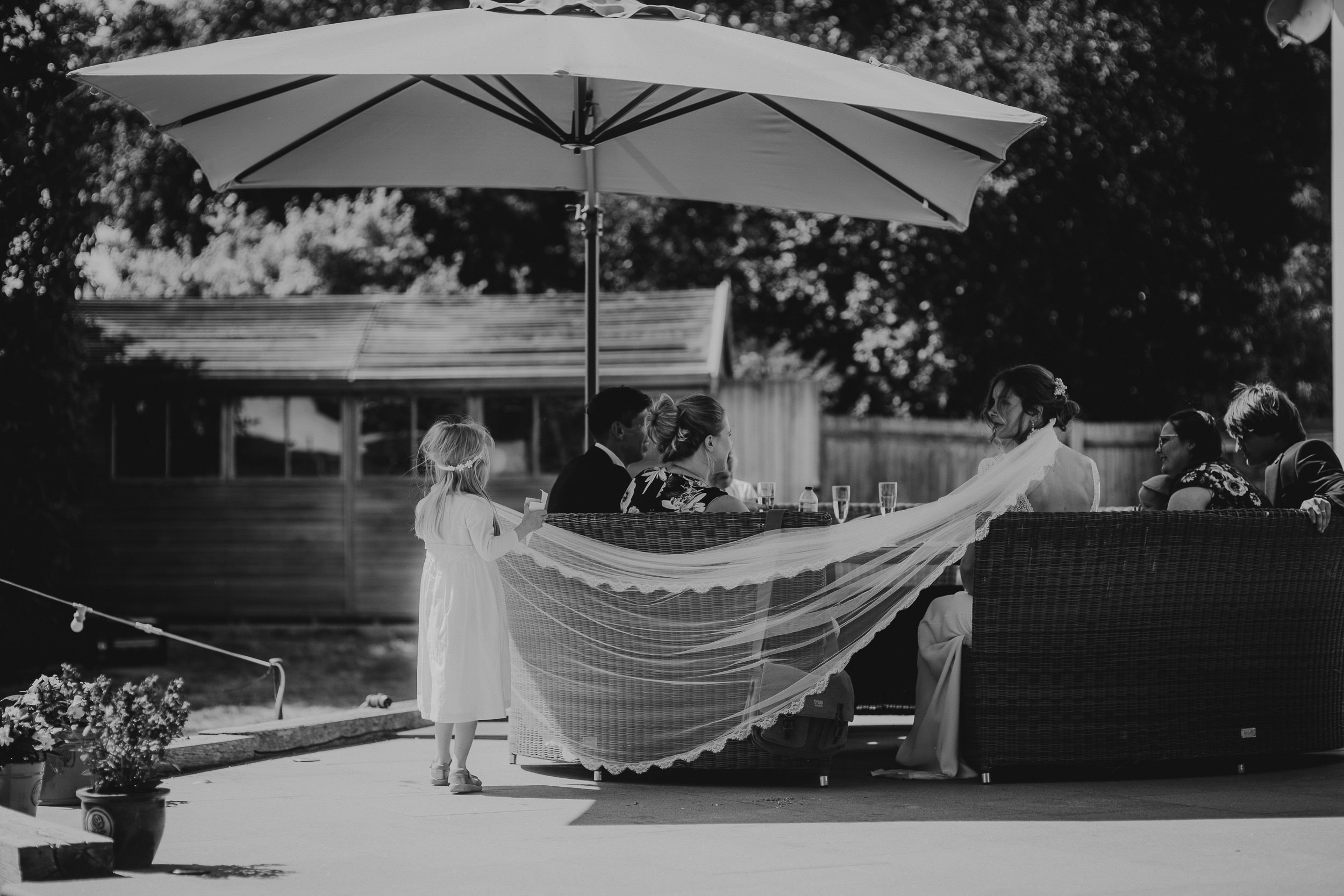 A black and white photo capturing a wedding couple under an umbrella.