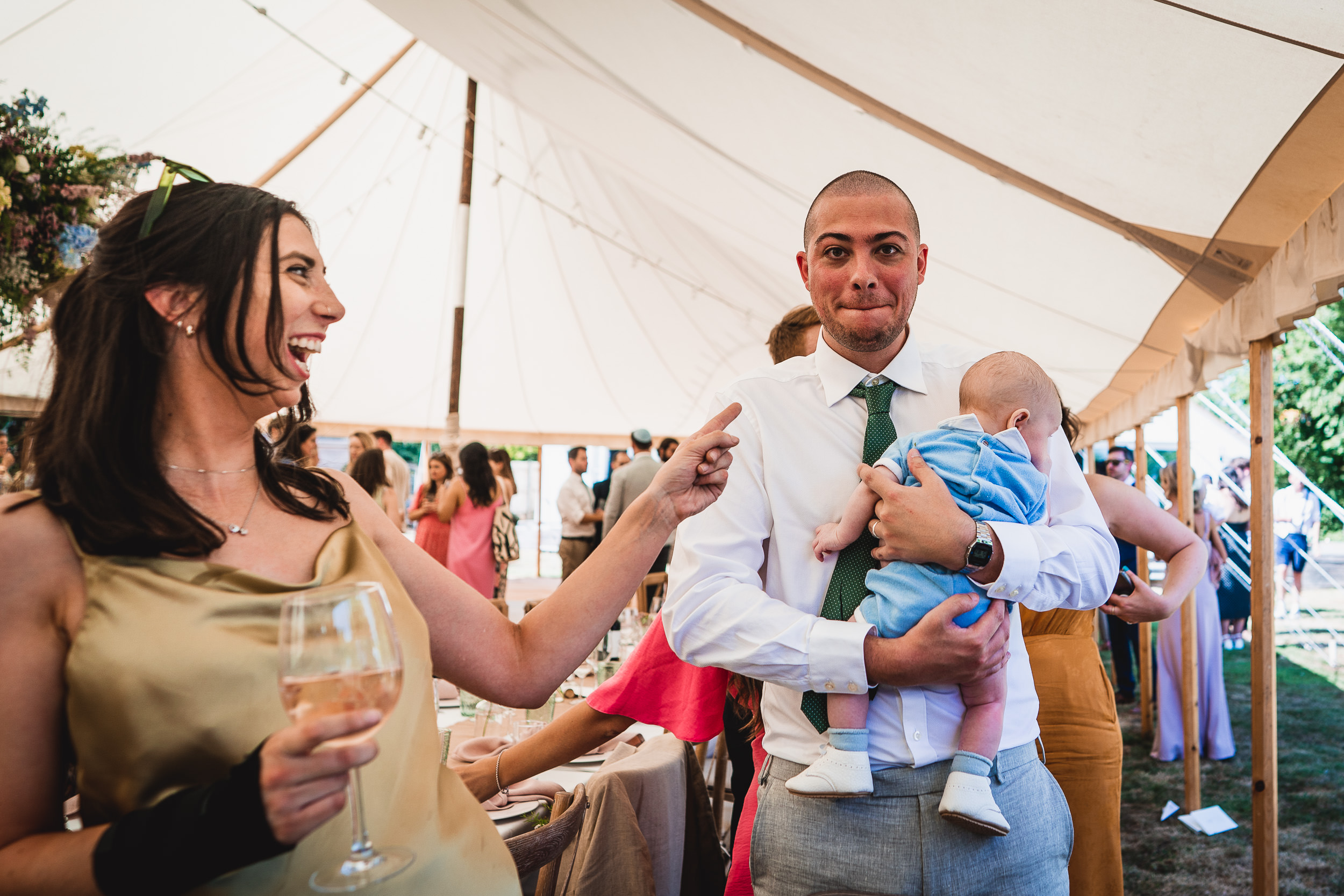 A woman holding a baby in a wedding tent.