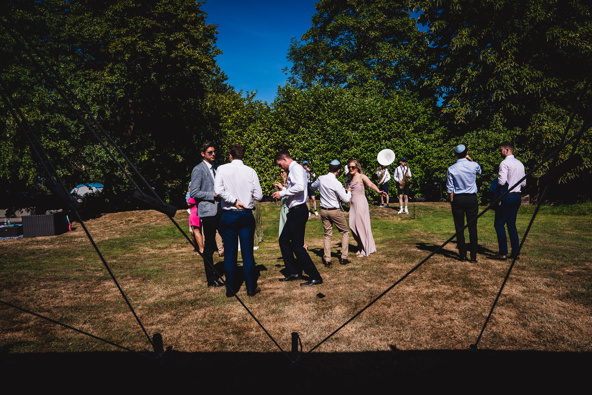 A group of people posing for a wedding photo in a grassy area.