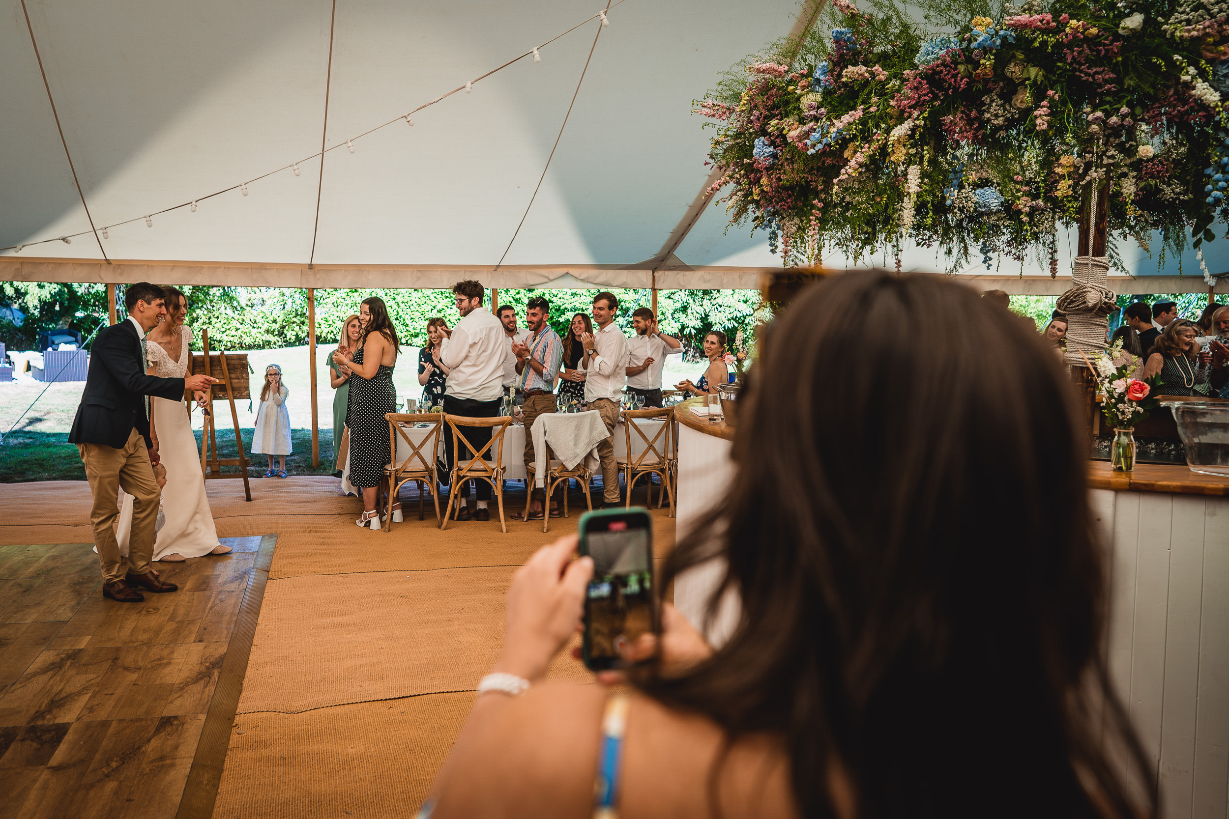 A wedding photographer capturing a couple's wedding photo in a tent.