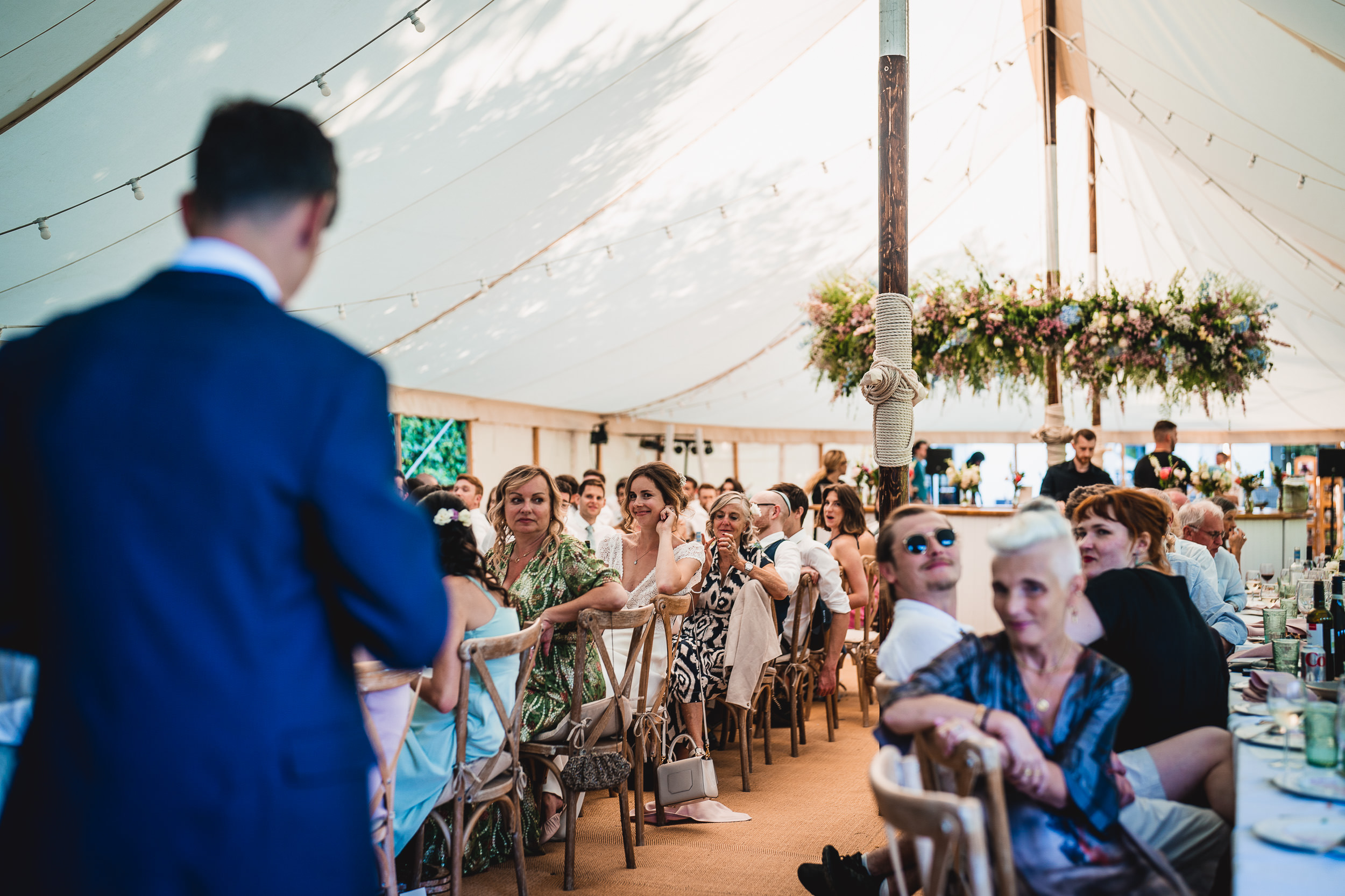 A groom is giving a speech at his wedding in a tent.