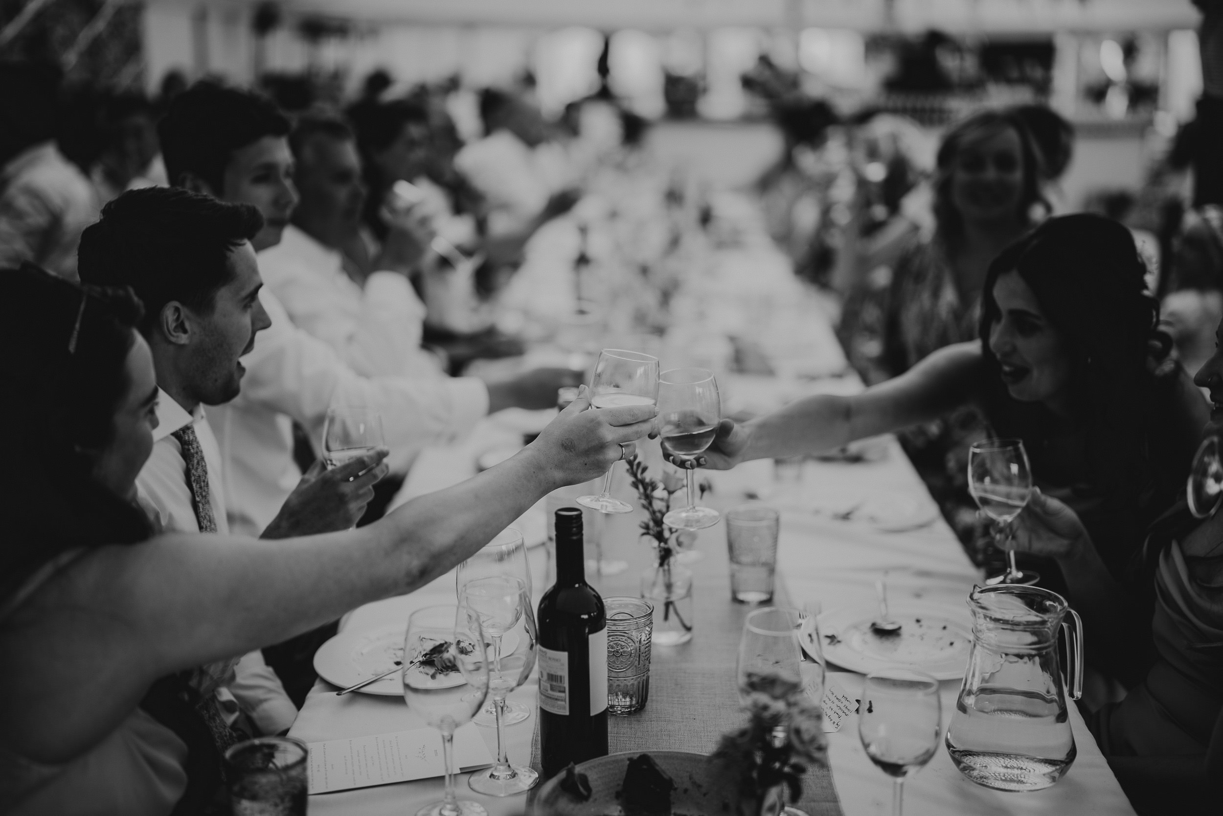A black and white wedding photo featuring a groom toasting.