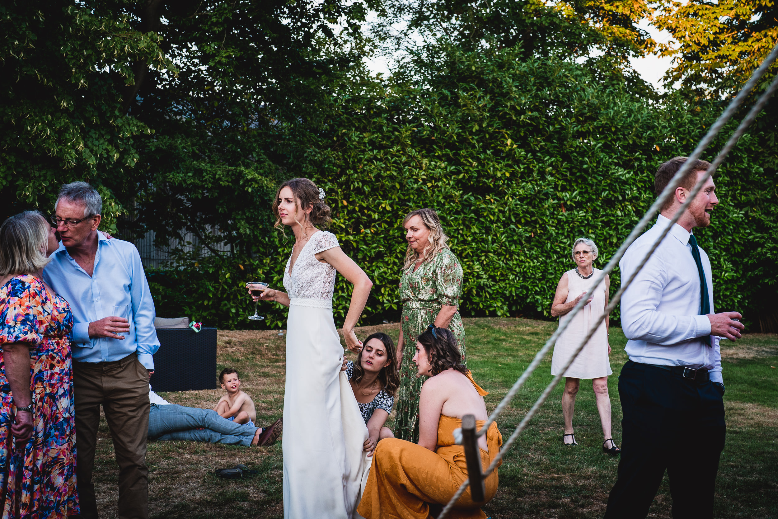 A group of people, including the groom, standing around a swing in a garden.
