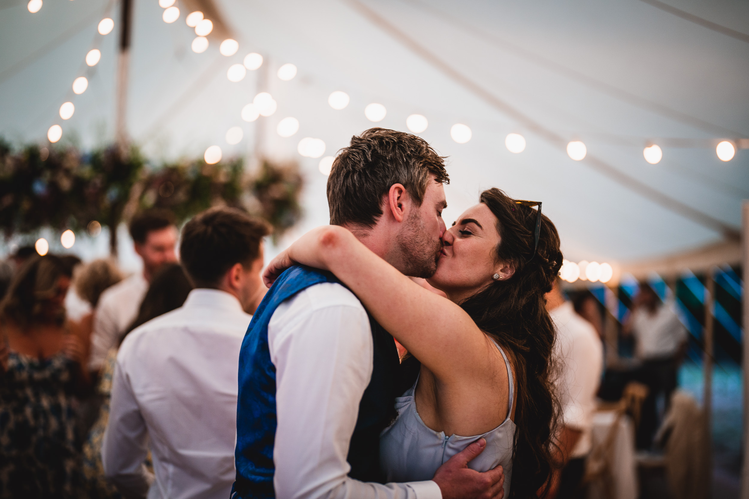 A wedding photo capturing the bride and groom's kiss under a tent.