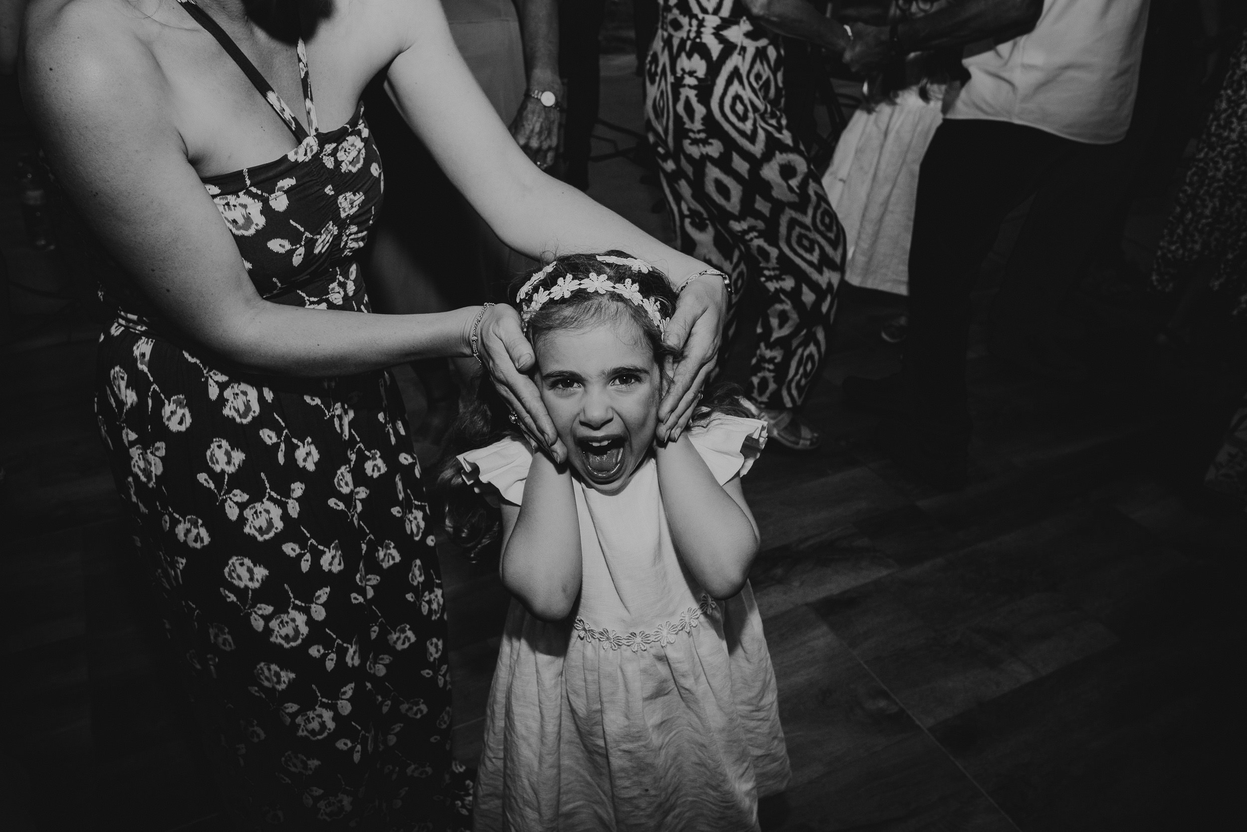 A little girl is being kissed by the bride on the dance floor at a wedding.