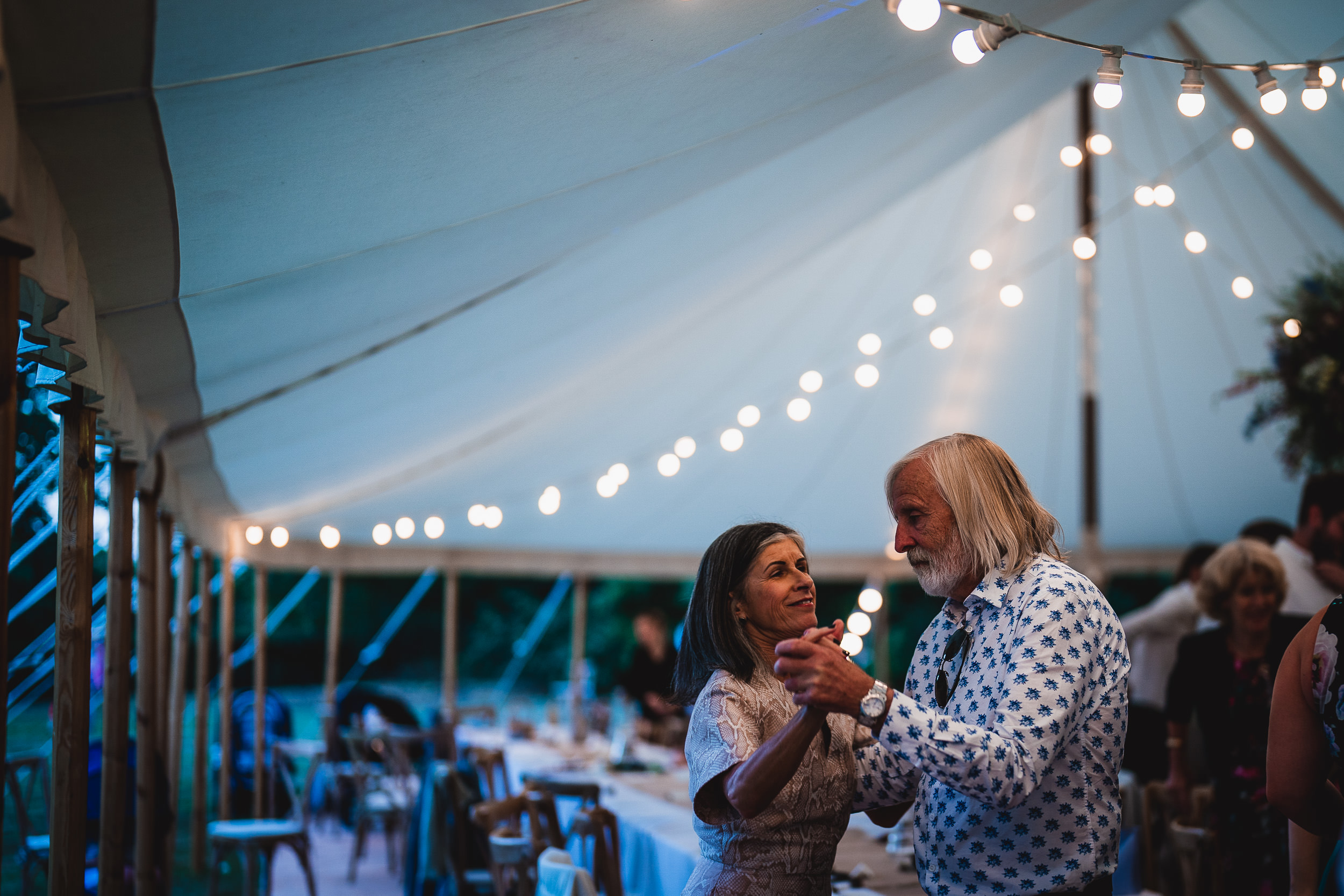 A bride and groom dancing at their wedding reception in a tent.