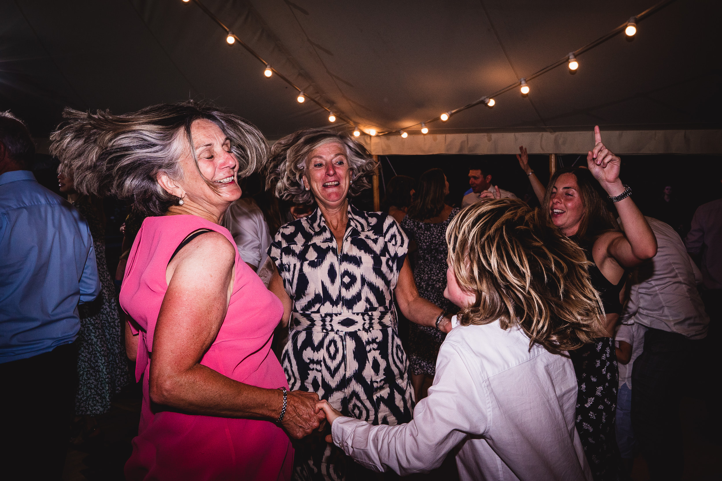 A bride posing in a wedding photo with a group of people dancing.