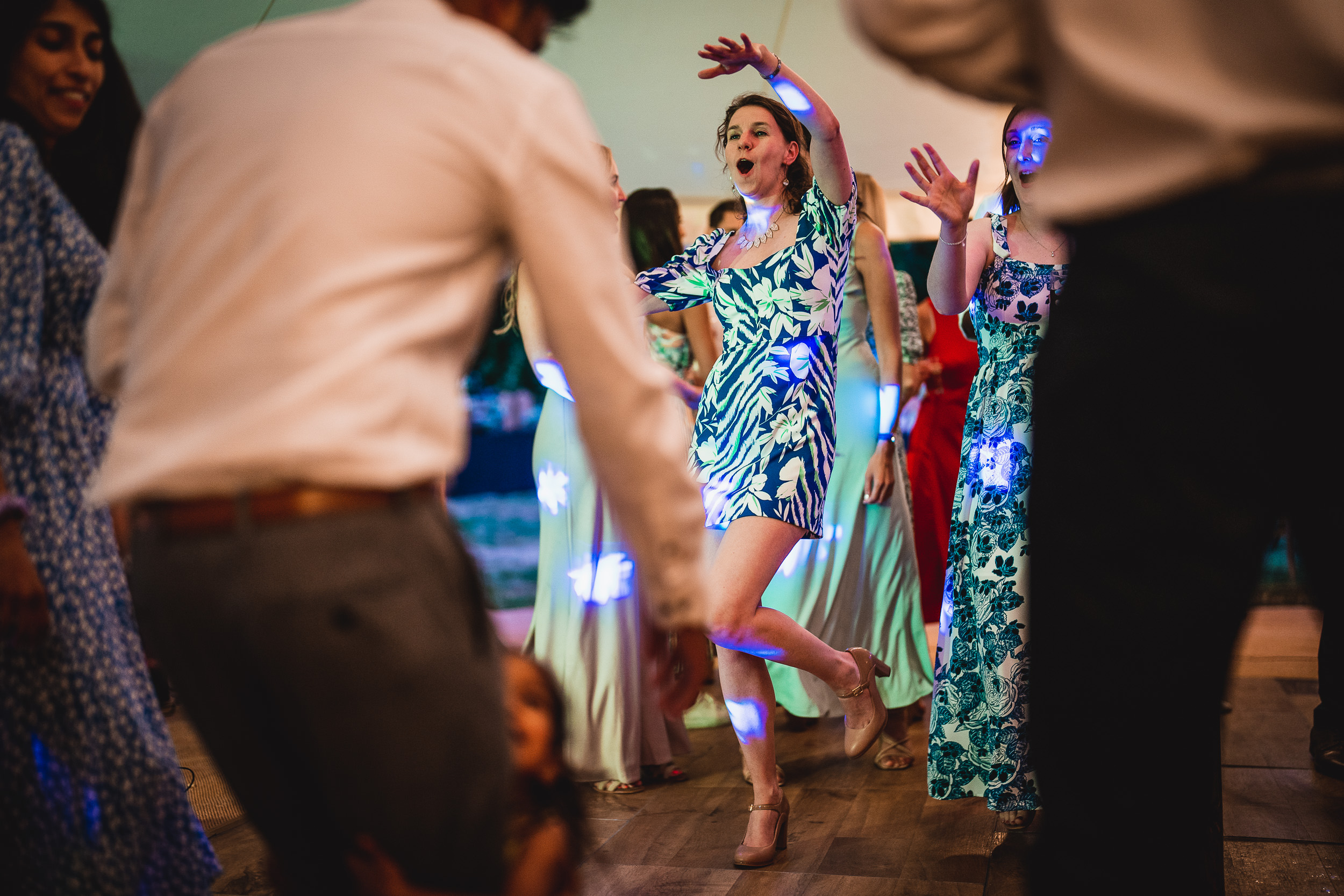A wedding photographer capturing the bride and guests dancing on the dance floor.