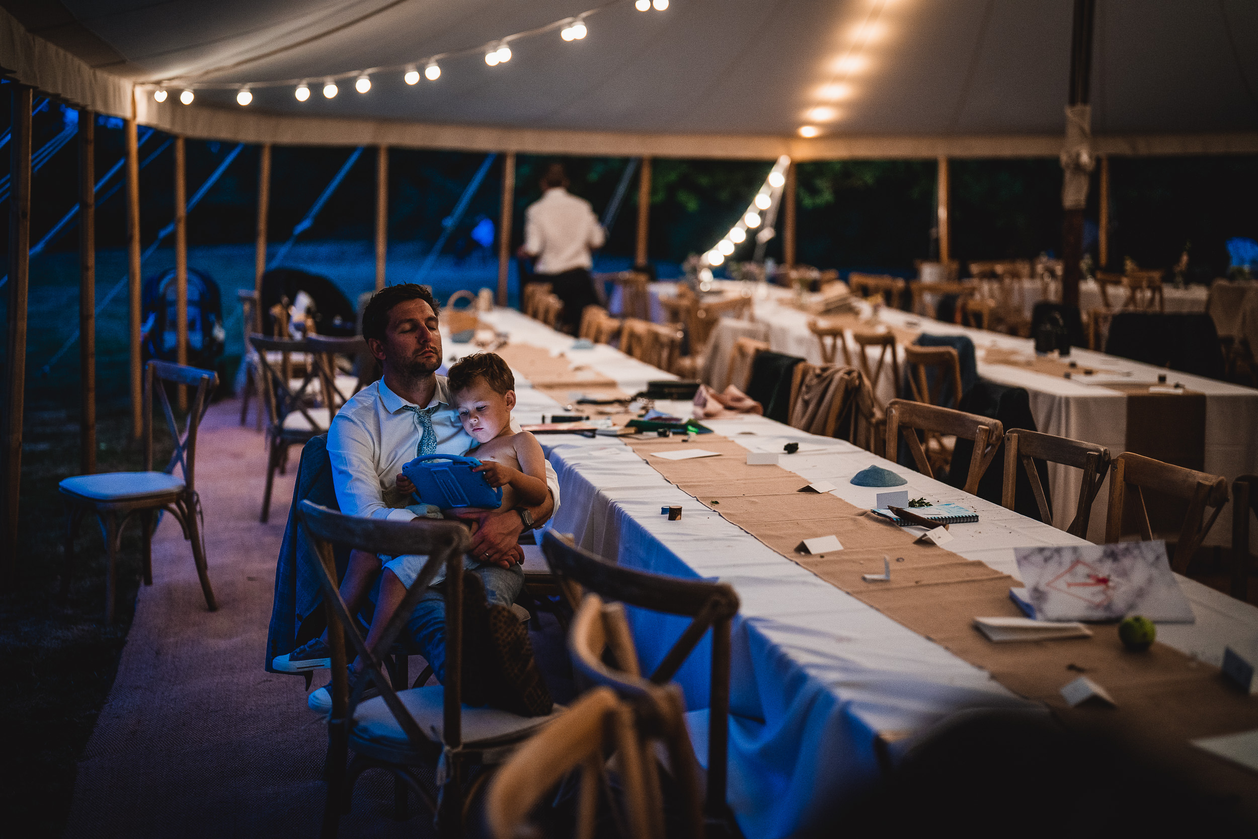 A bride and groom captured in a wedding photo, sitting together at a table inside a tent.