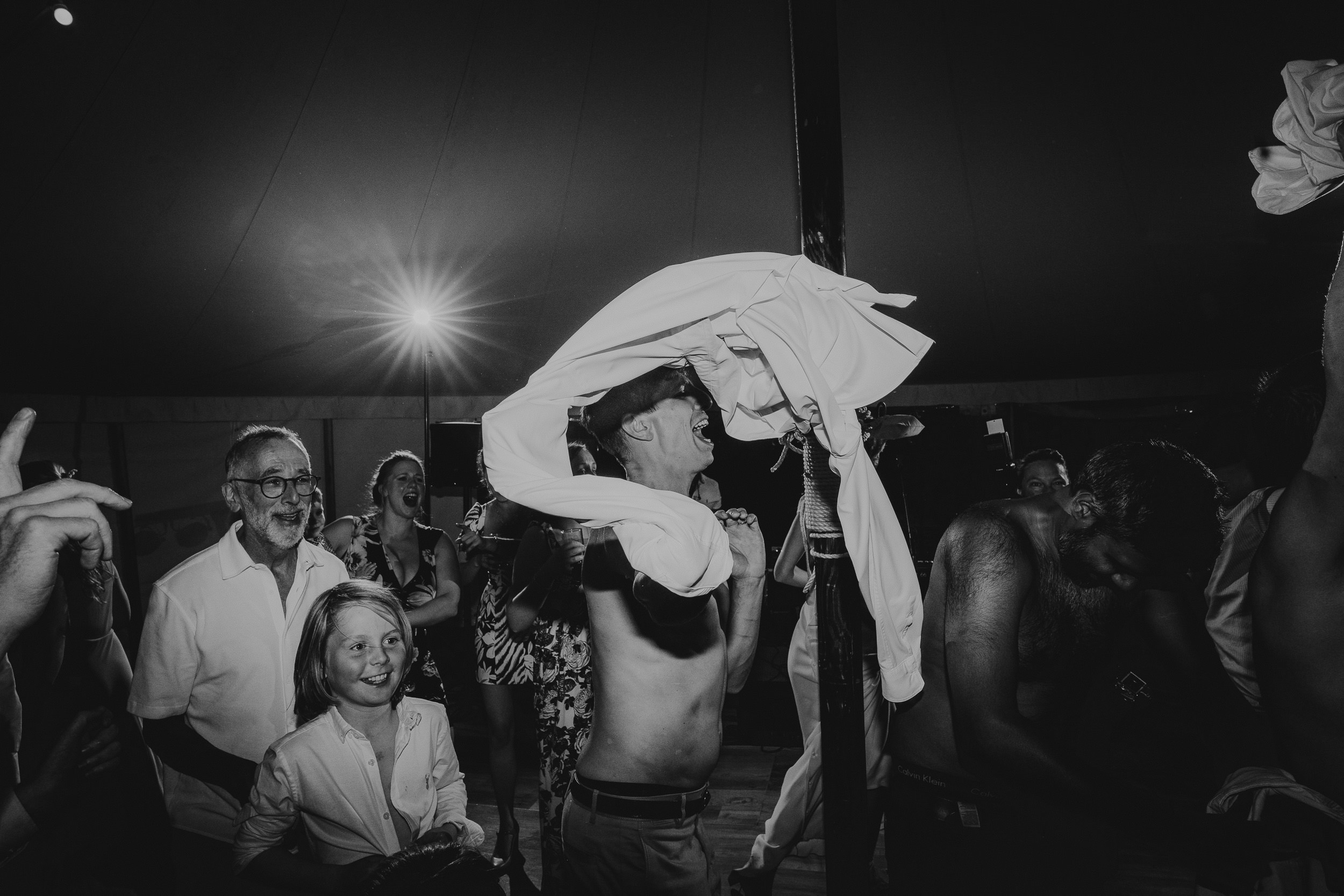A groom is holding a towel in the air at his wedding.