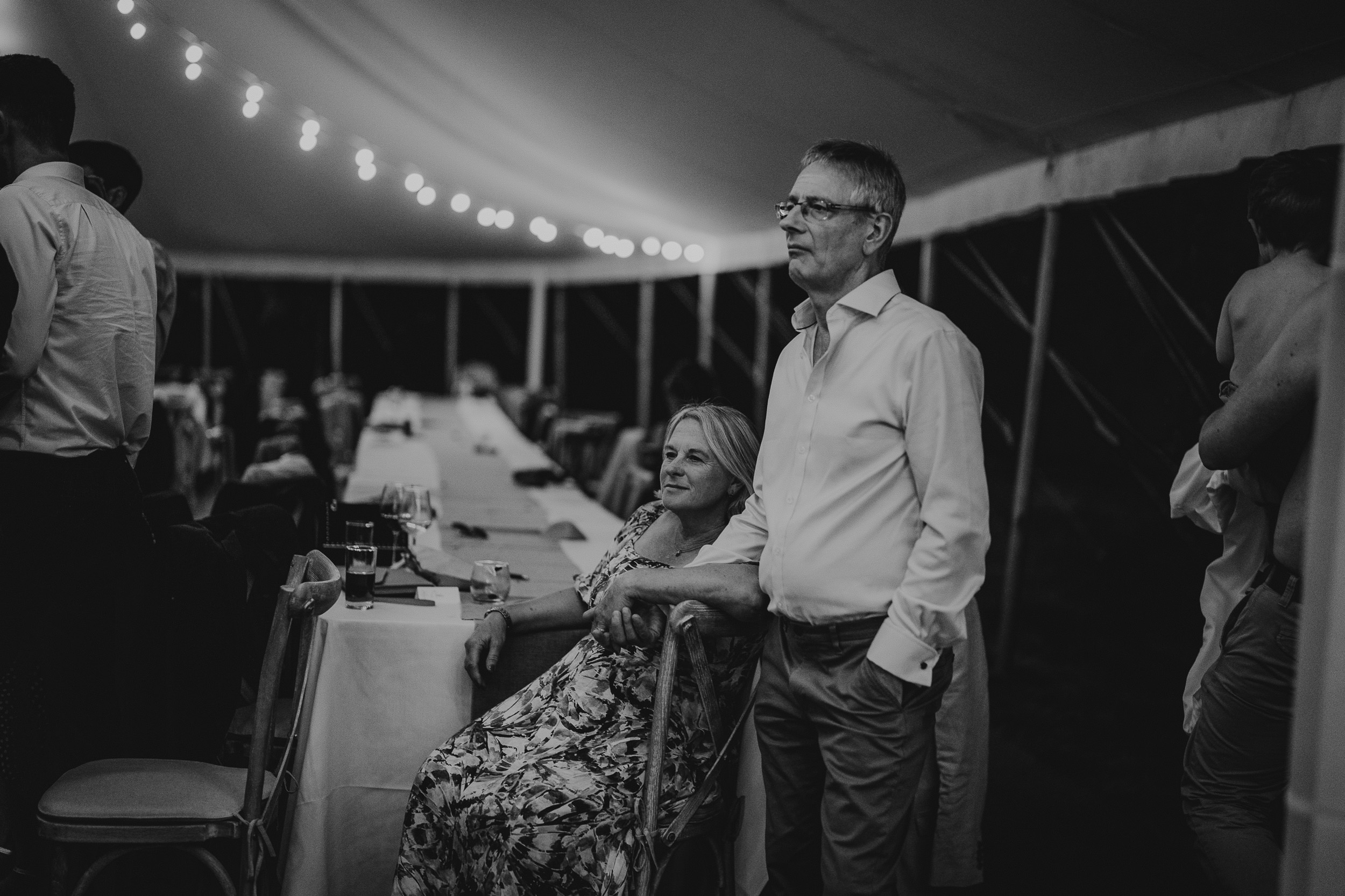 A bride and groom sitting at a table in a wedding tent.