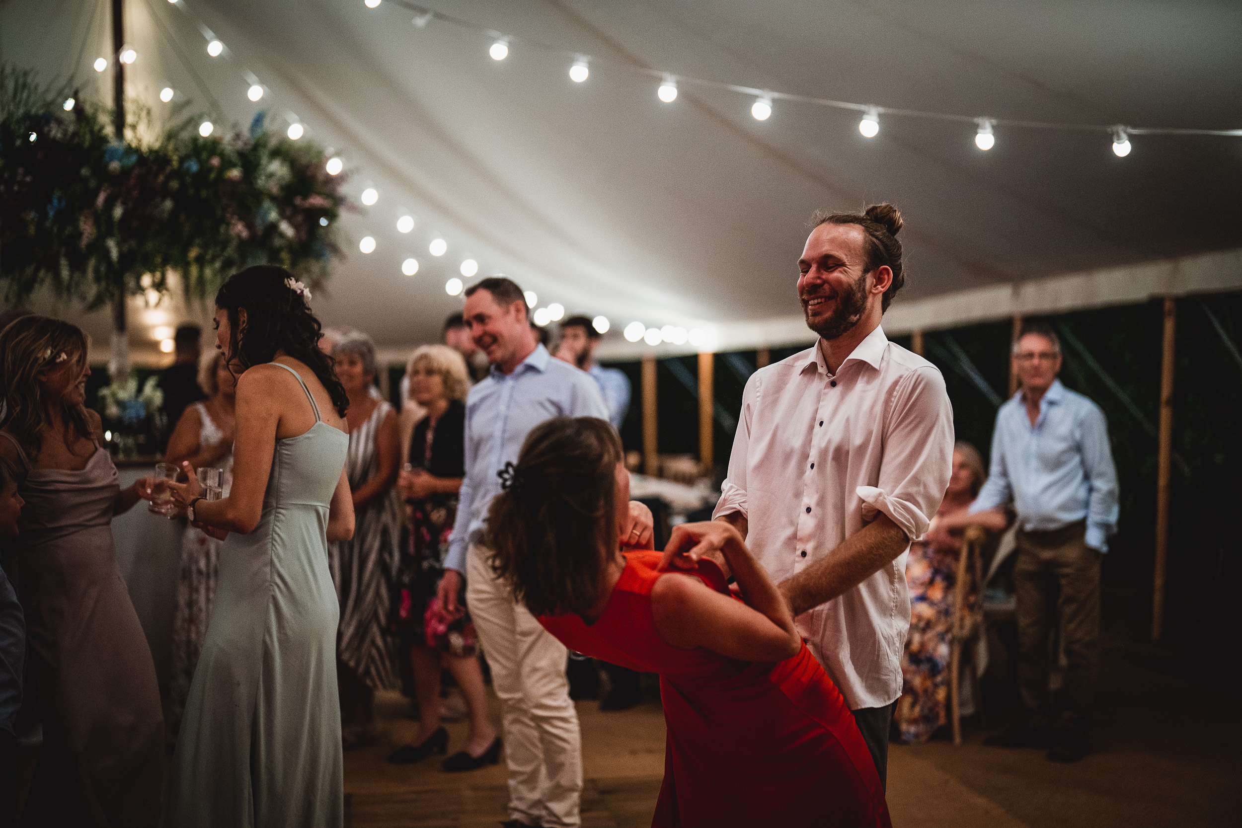 A couple dancing in a tent at their wedding, captured by a wedding photographer.