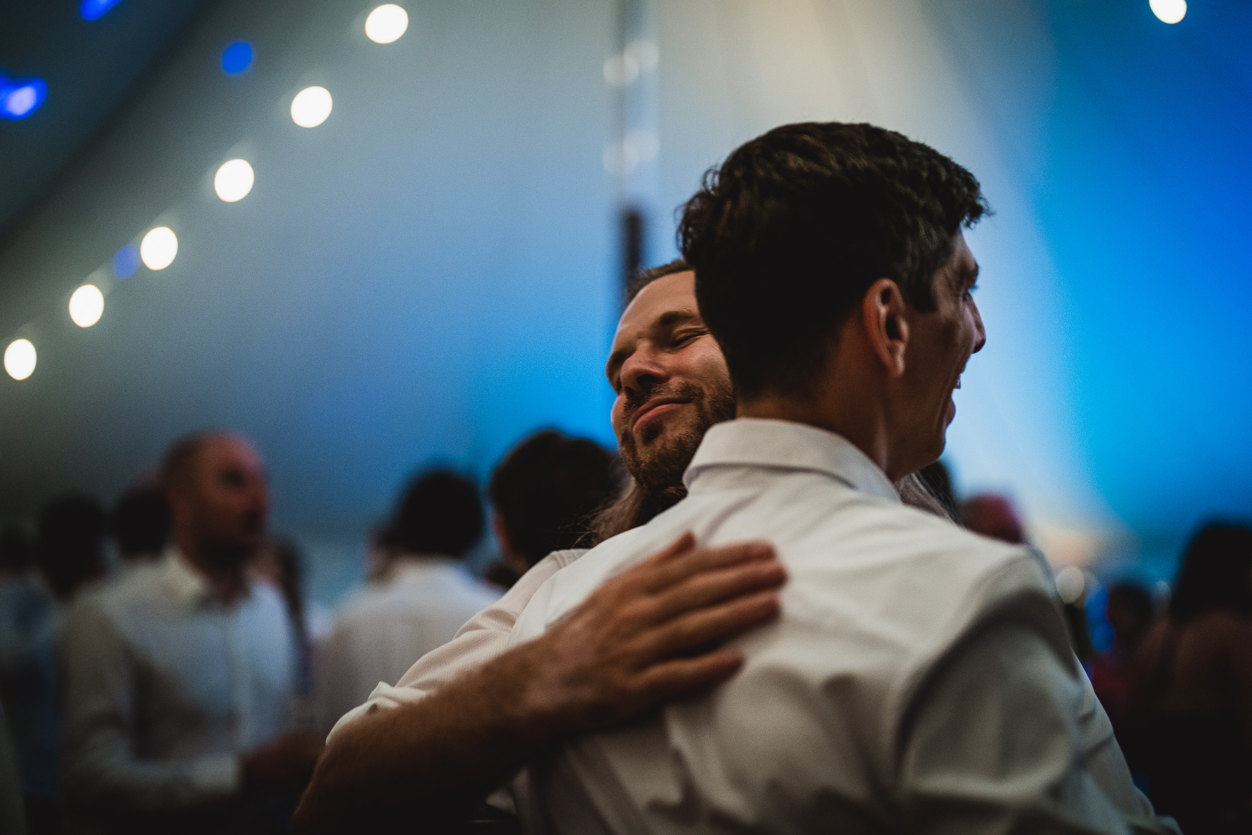 Two grooms hugging each other in their wedding photo.