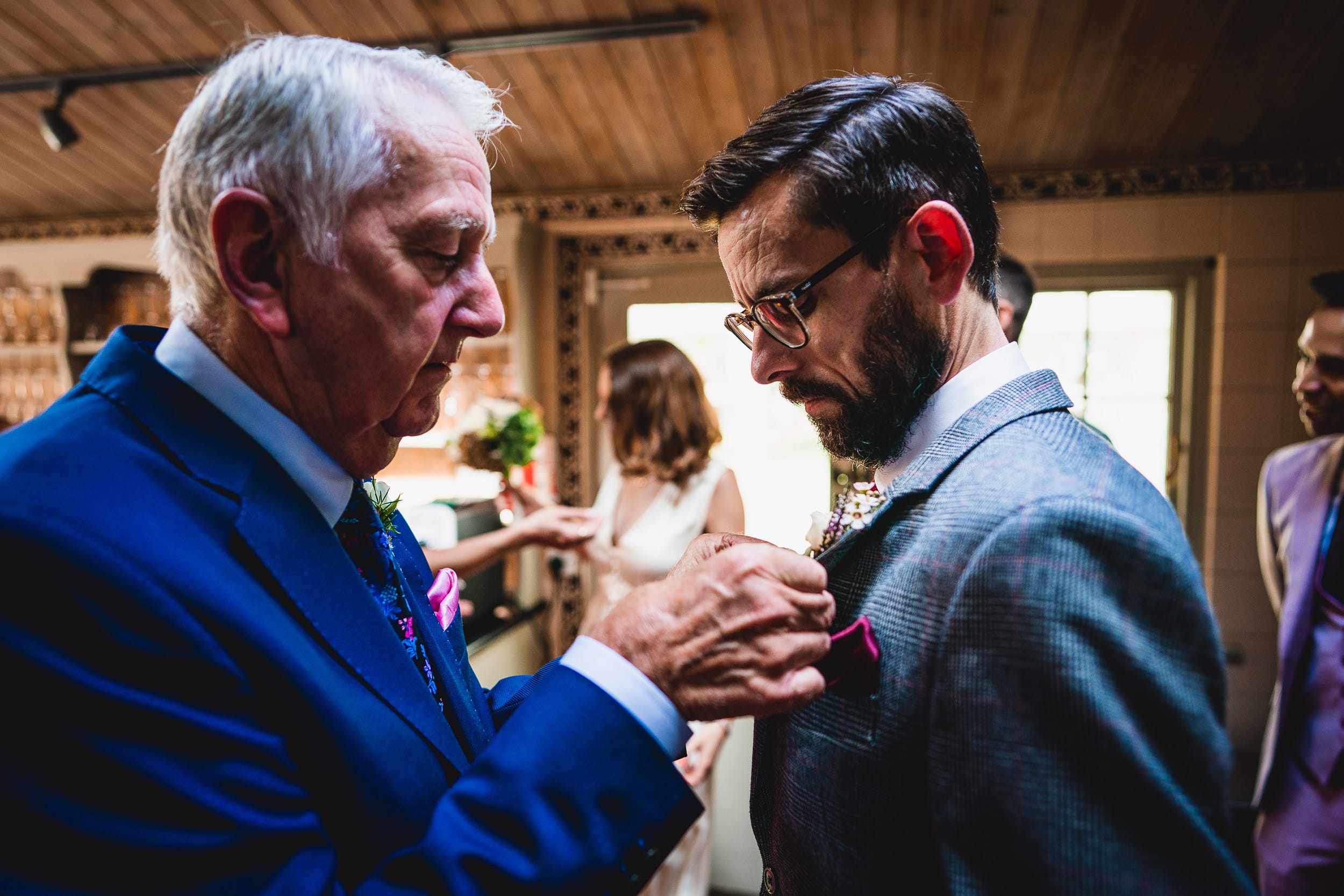 A man in a suit adjusts another man's tie at a Surrey Wedding.