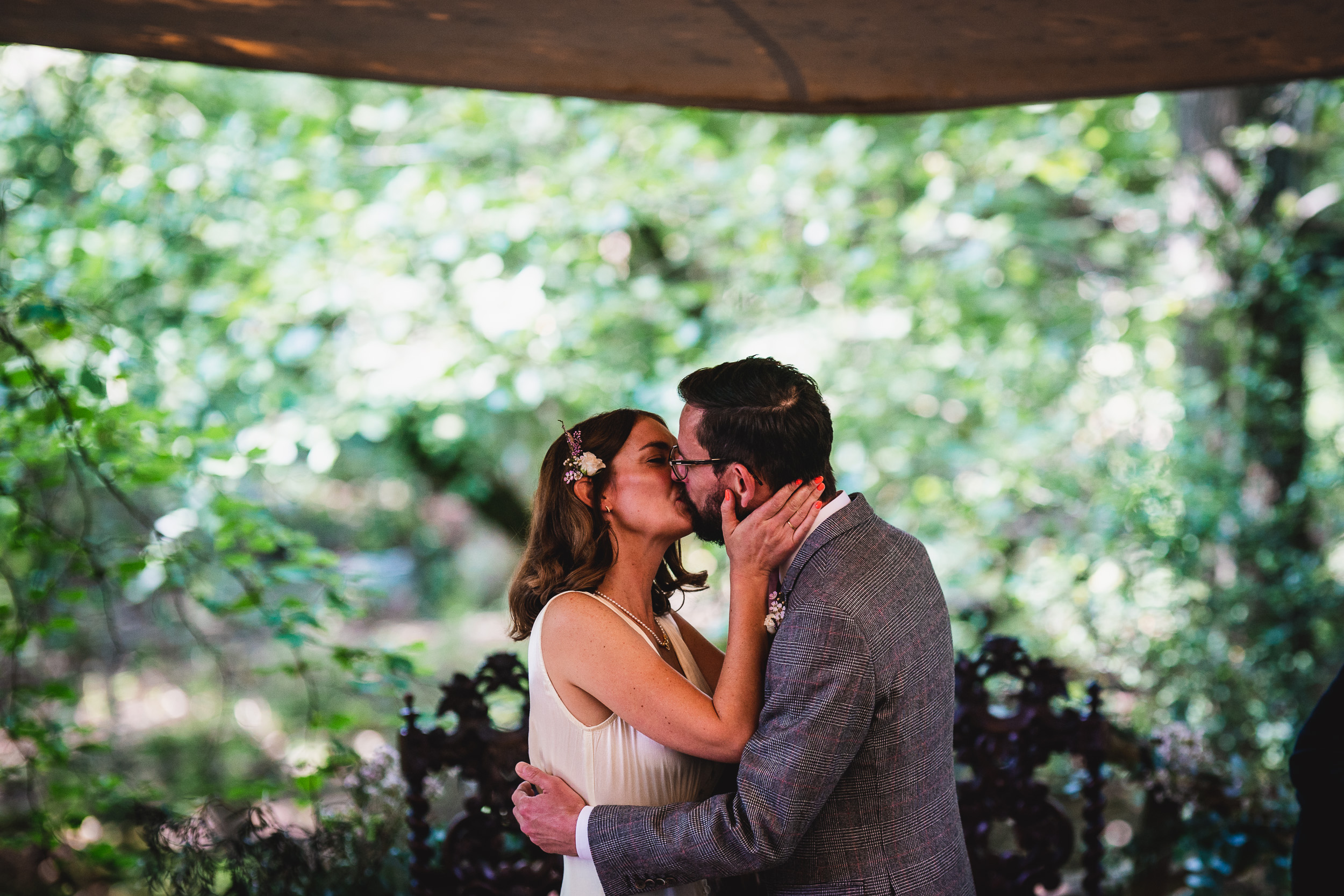 A bride and groom kissing under a tent in the woods at Ridge Farm, Surrey Wedding.