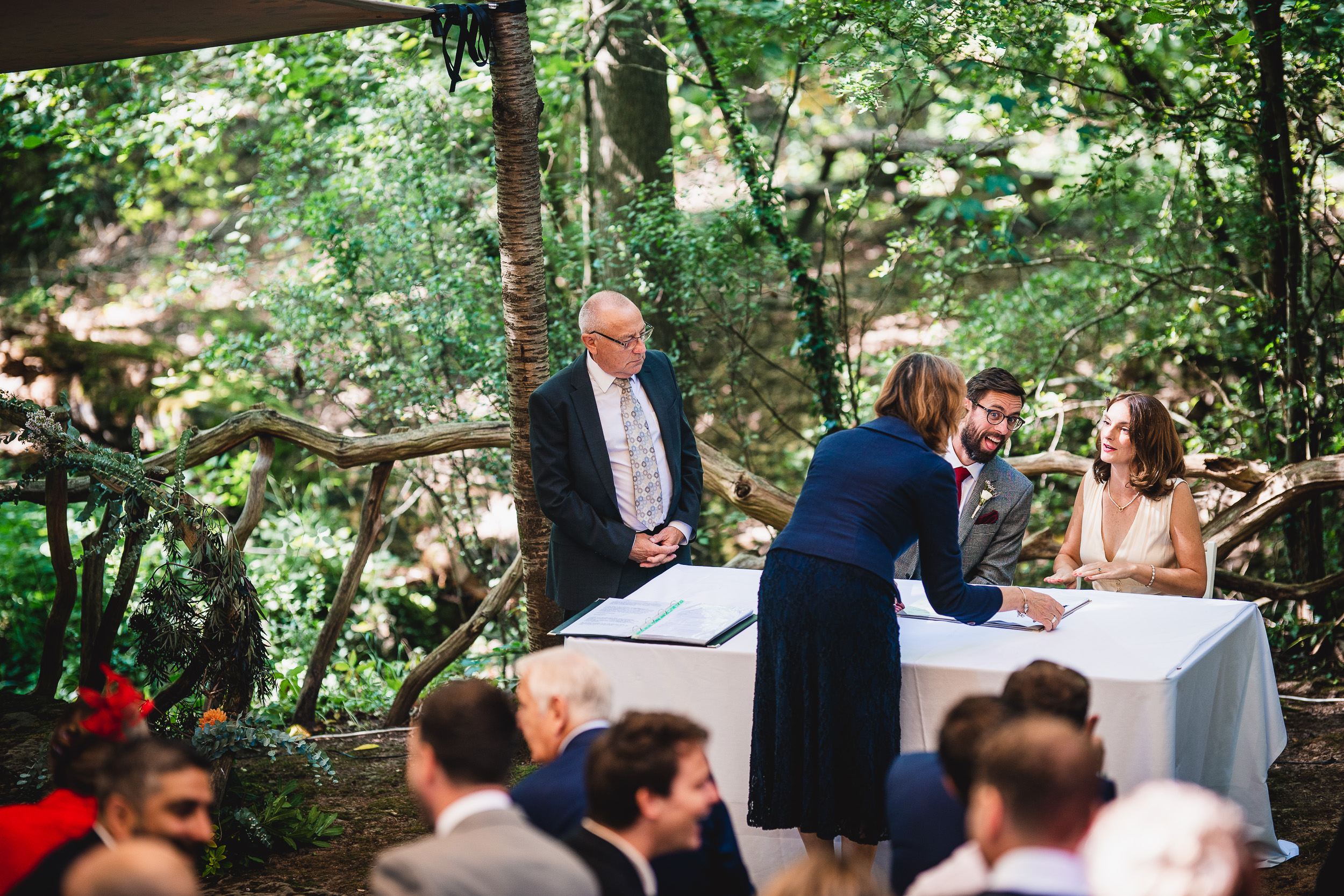 A bride and groom signing their Surrey wedding vows in the woods at Ridge Farm.