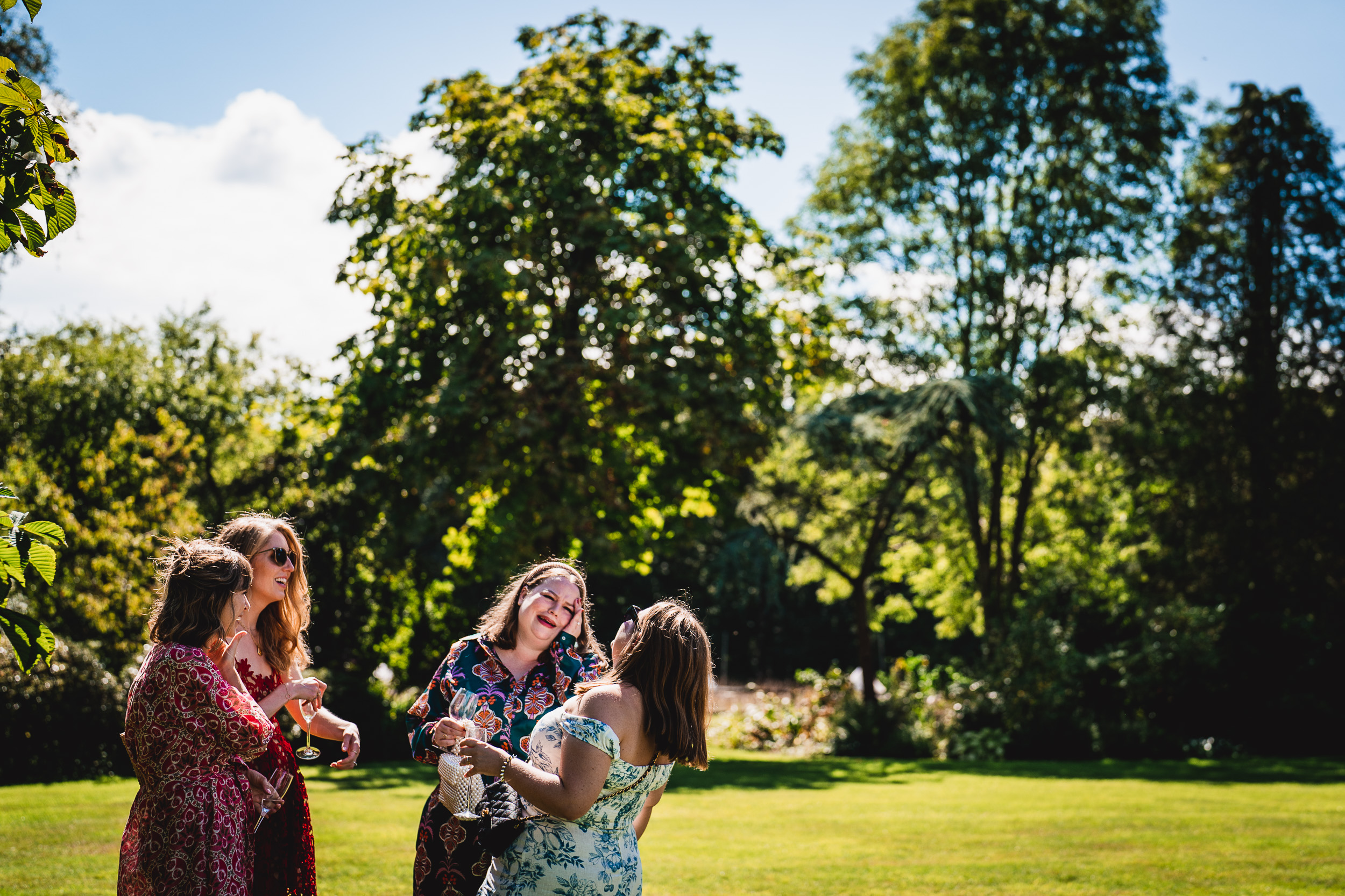 A group of bridesmaids laughing in the grass at a Surrey Wedding.