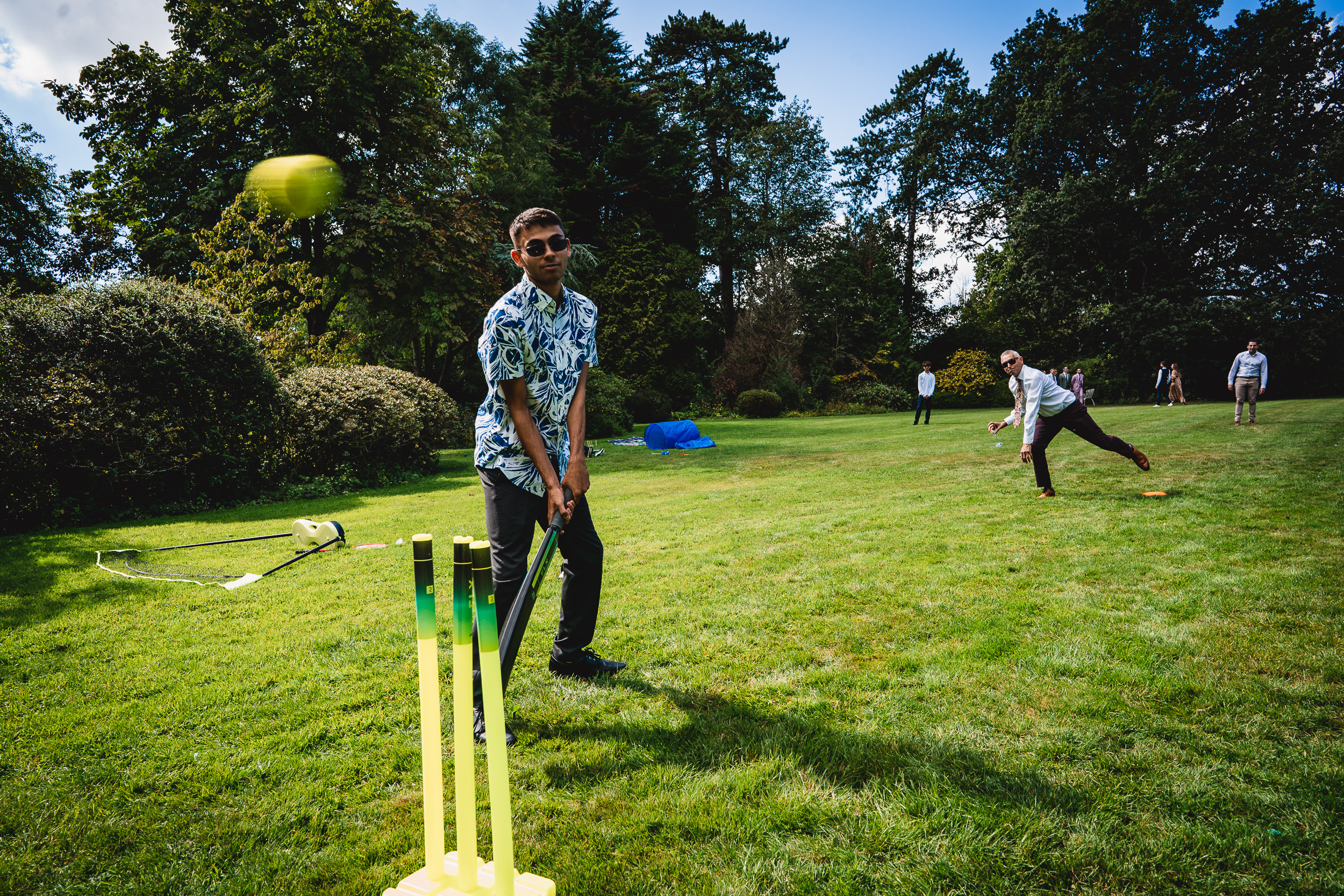 A group of people playing cricket in the picturesque Ridge Farm garden in Surrey.