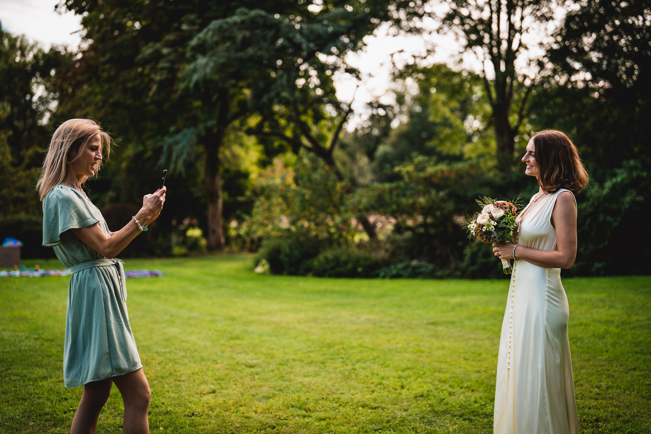 Two brides taking a picture of each other at Ridge Farm in Surrey for their wedding.