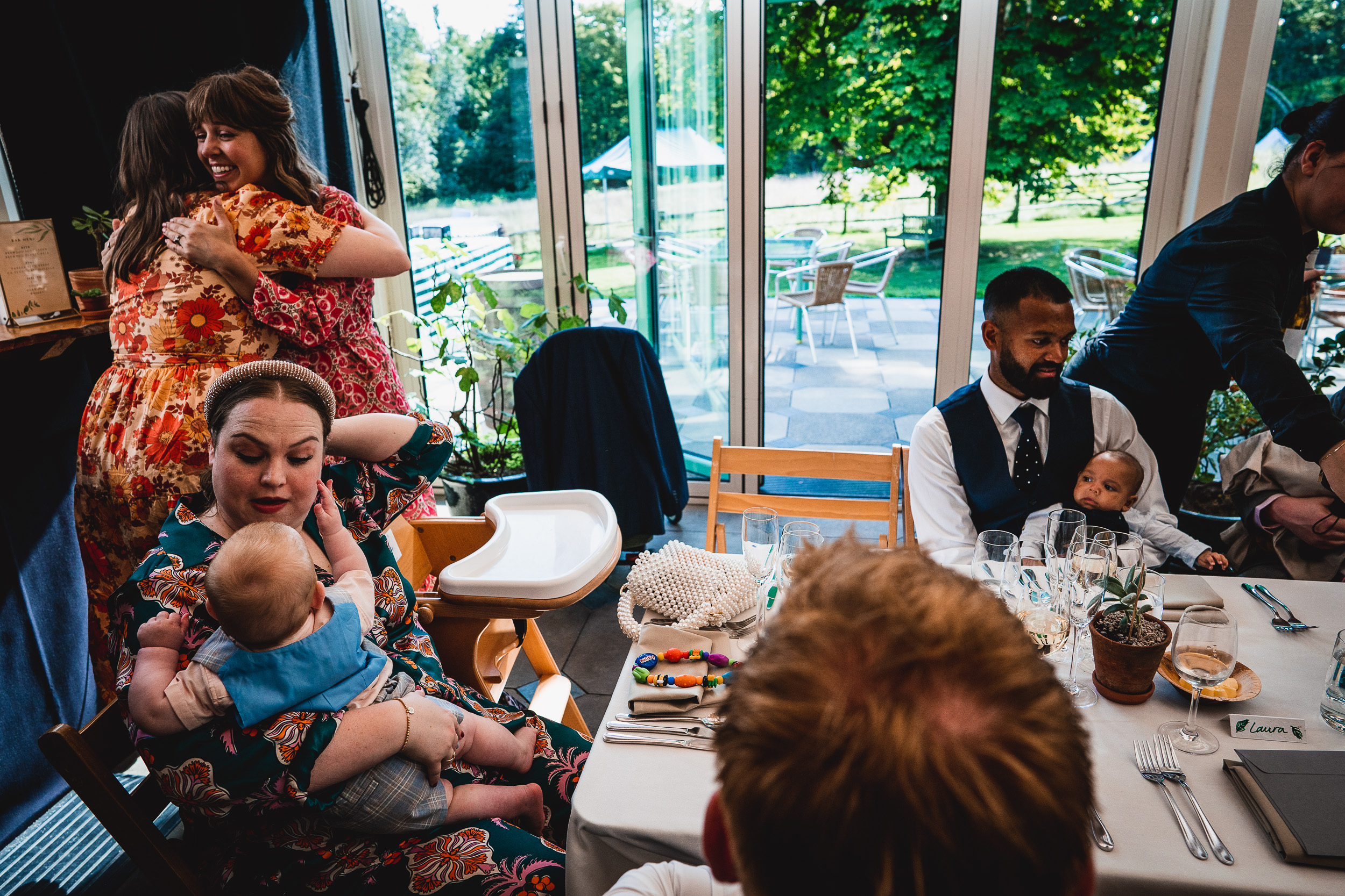 A group of people sitting at a table with a Surrey Wedding in their arms.