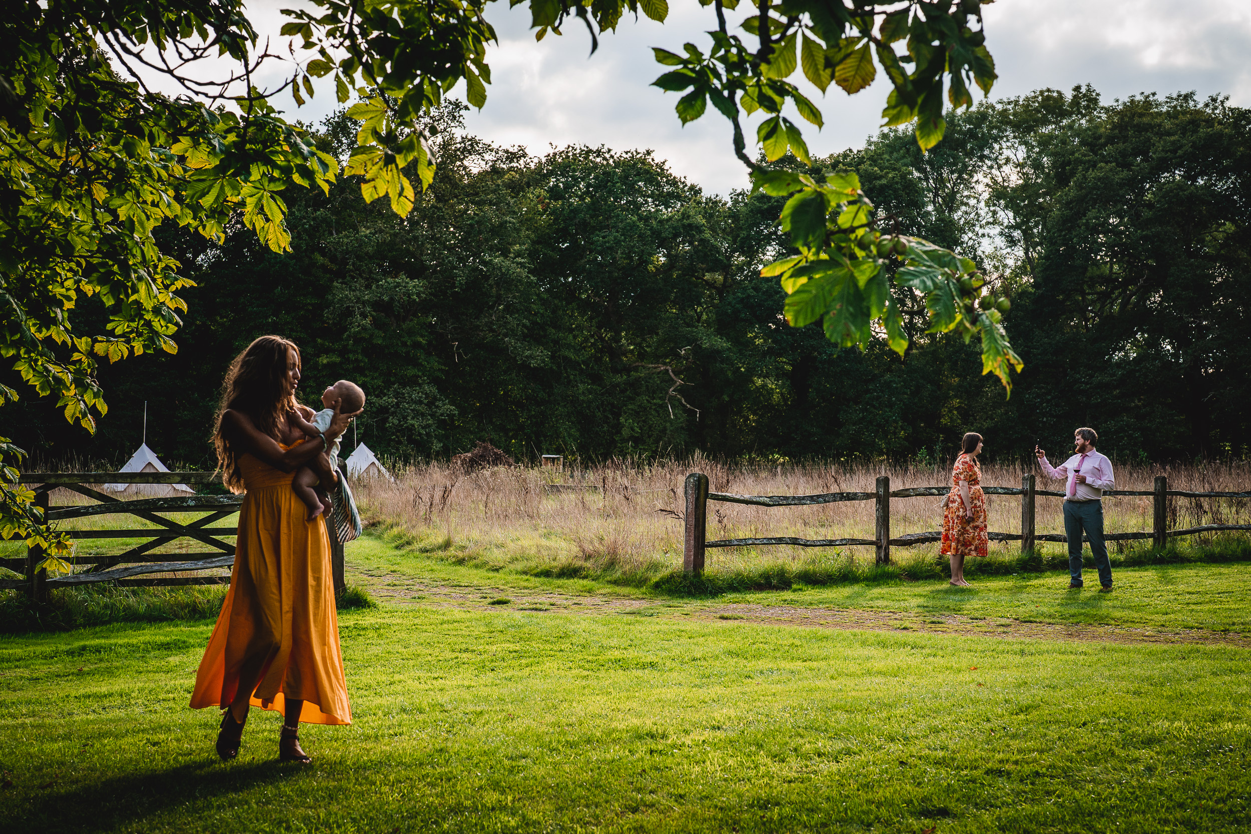 A woman in a yellow dress and a baby in a grassy field at Ridge Farm.